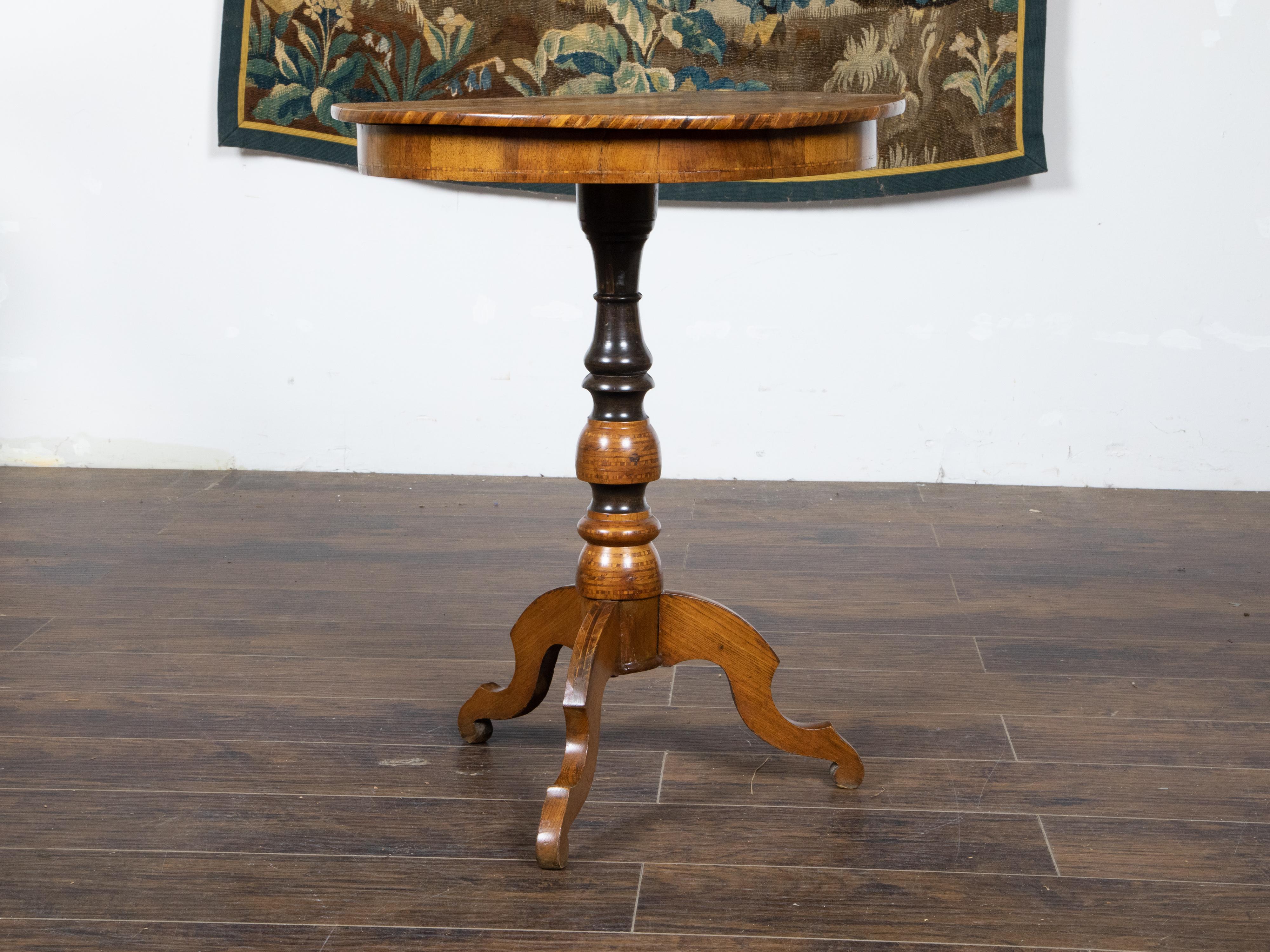 An Italian walnut guéridon side table from the late 19th century with round marquetry decorated top, carved and ebonized pedestal and tripod base. Created in Italy during the last quarter of the 19th century, this guéridon table attracts our