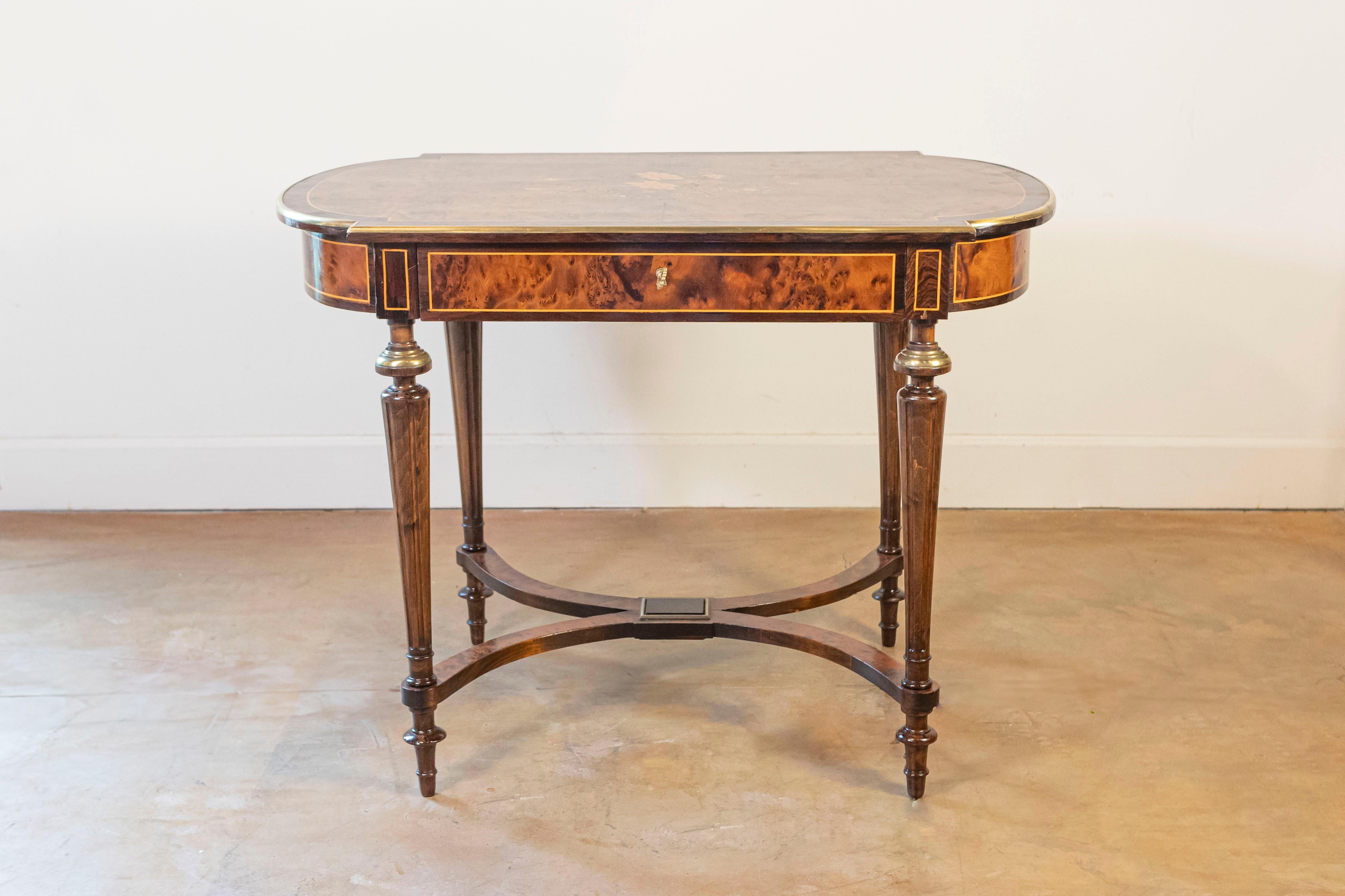 Mesa auxiliar italiana de nogal y caoba de hacia 1890 con marquetería floral en la parte superior, adornos de latón, un solo cajón, patas cónicas acanaladas y cruceta en forma de X. Descubre la quintaesencia de la artesanía italiana en esta
