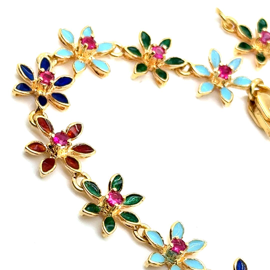 Splendidamente realizzato in Italia, questo bracciale vibrante presenta fiori smaltati multicolore incastonati in oro giallo massiccio 18kt. Impreziosito da 14 rubini naturali per un totale di 0,42 carati, combina un gioco di colori con un'elegante