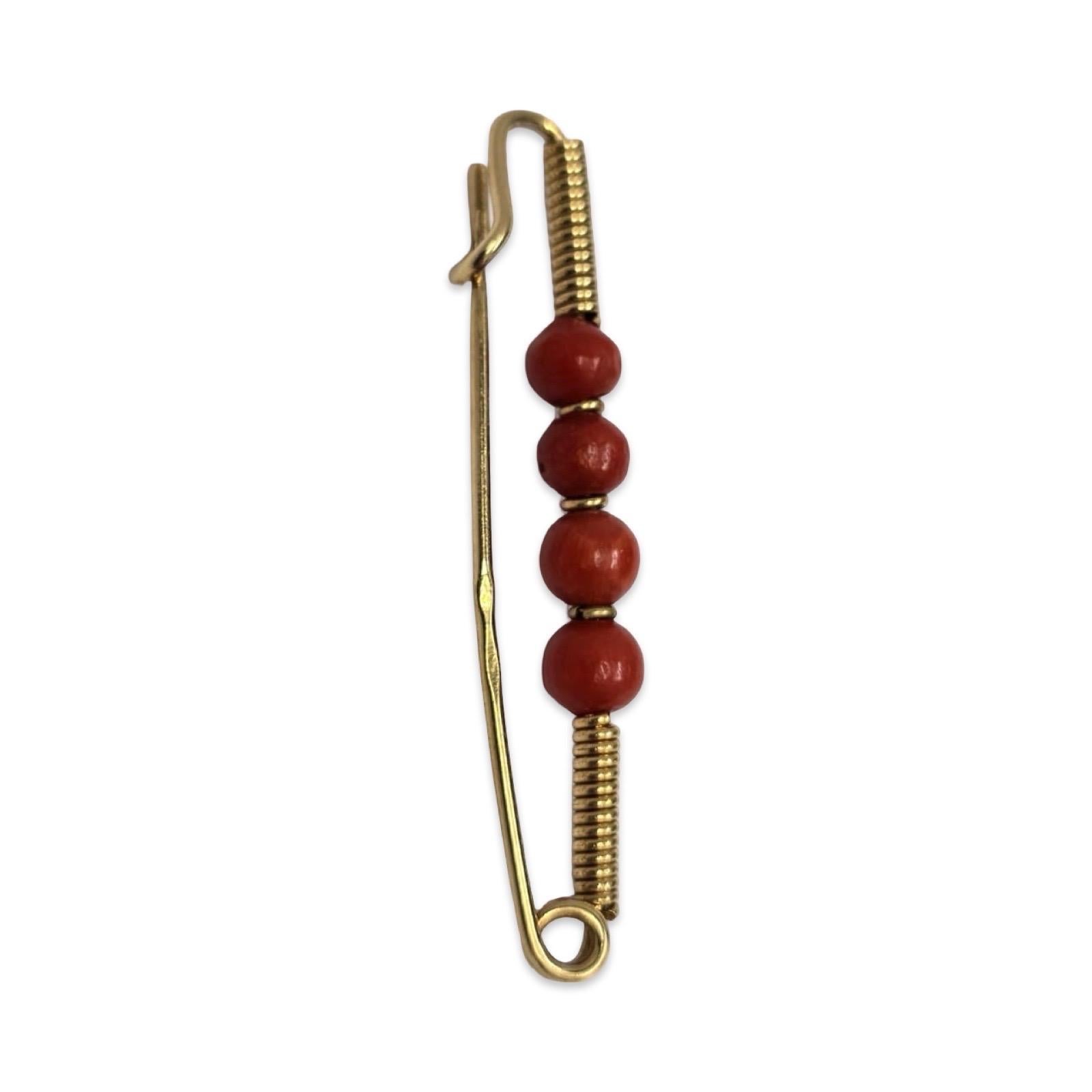 Una spilla da balia in oro giallo 18 carati splendidamente realizzata a mano con cinque perle di corallo rosso naturale del Mediterraneo di circa 4,4 mm ciascuna, per un totale di circa 1,50 carati. Il design presenta i classici dettagli della