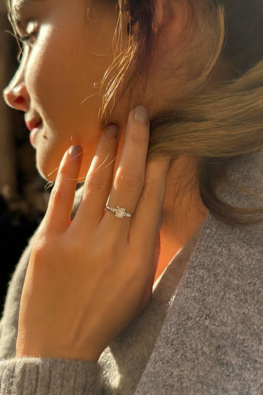 A refined Italian creation in 18K white gold, this elegant ring showcases timeless minimalism and perfect proportions.
At its heart lies a 1.05-carat emerald-cut diamond, flanked by tapered baguette side stones totaling approximately 0.20 carats,