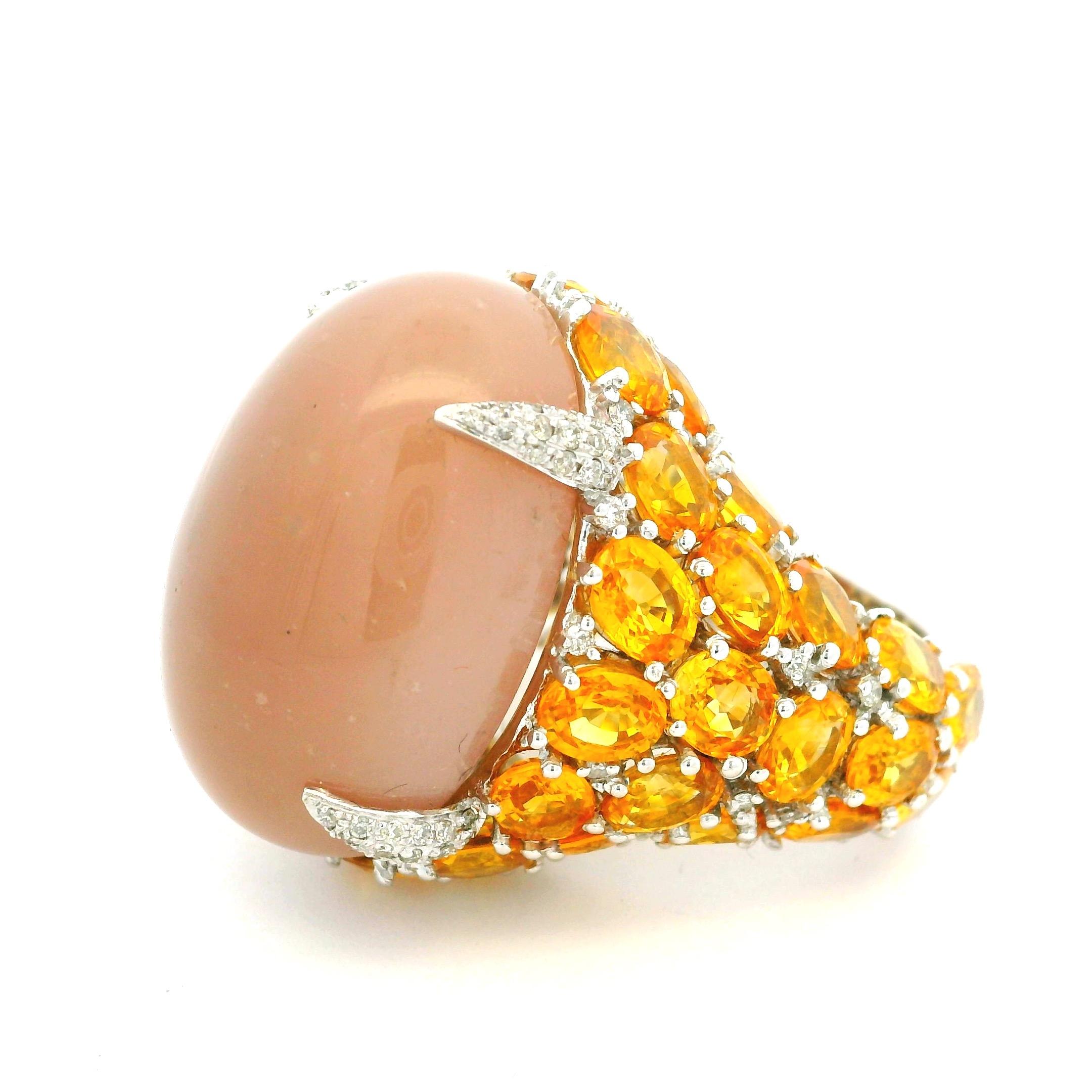 Cette spectaculaire bague de cocktail italienne contemporaine en or blanc 18 carats est ornée d'une pierre de lune cabochon pesant environ 28,00 carats. L'éclat lumineux de la pierre de lune est rehaussé par un somptueux entourage de 40 saphirs