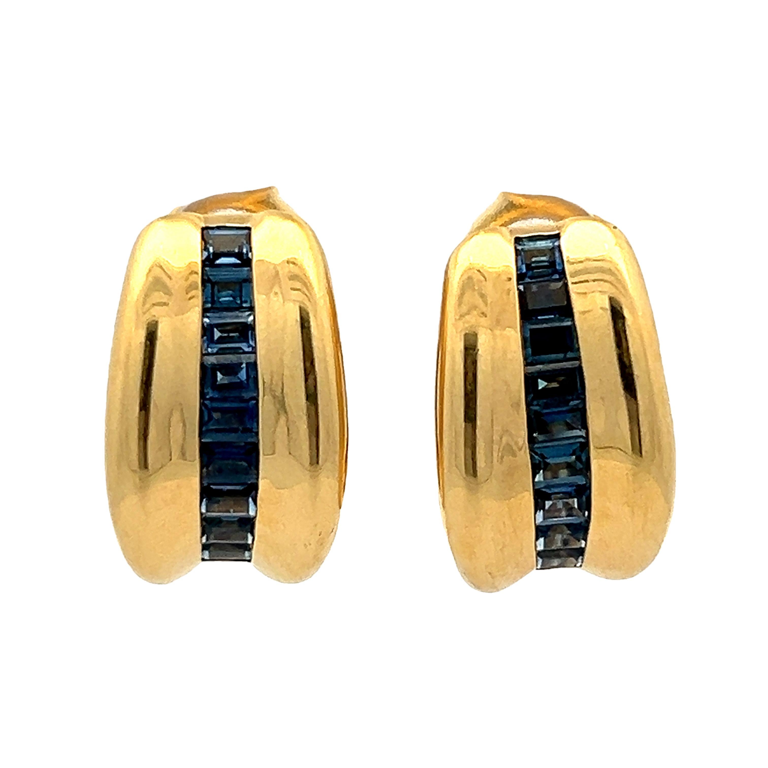 D'une sophistication européenne intemporelle, ces boucles d'oreilles italiennes sont réalisées en or jaune 18 carats (poinçonné 750 Italie) et présentent un profil élégant et contemporain. Un canal central de saphirs bleus profonds taillés à la