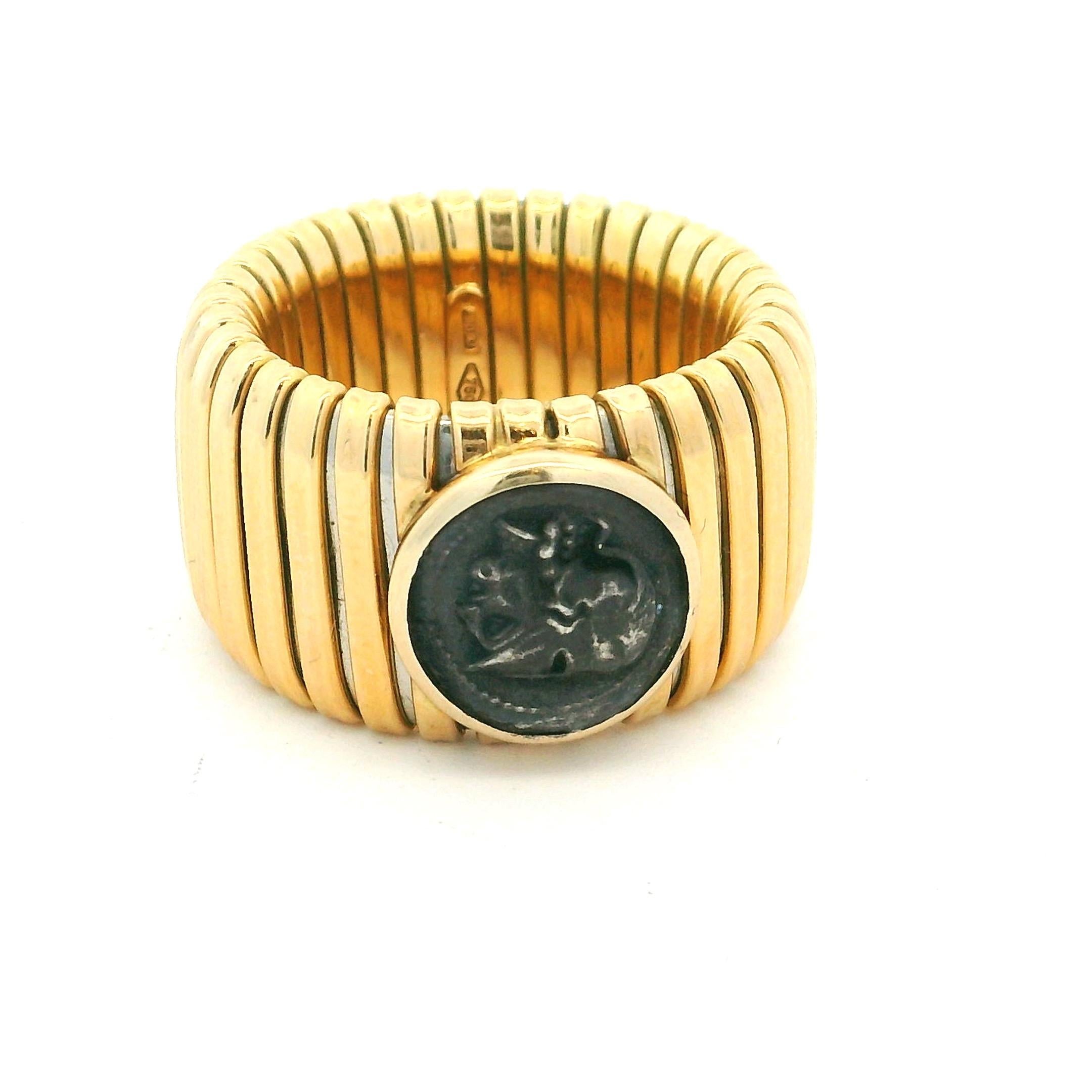 Bague vintage en or jaune 18 carats, conçue dans le style iconique des tubogas. La large bande nervurée, d'une largeur de 0,5 pouce, est centrée sur une pièce de monnaie ancienne sertie d'un chaton, alliant ainsi un design moderniste audacieux à un