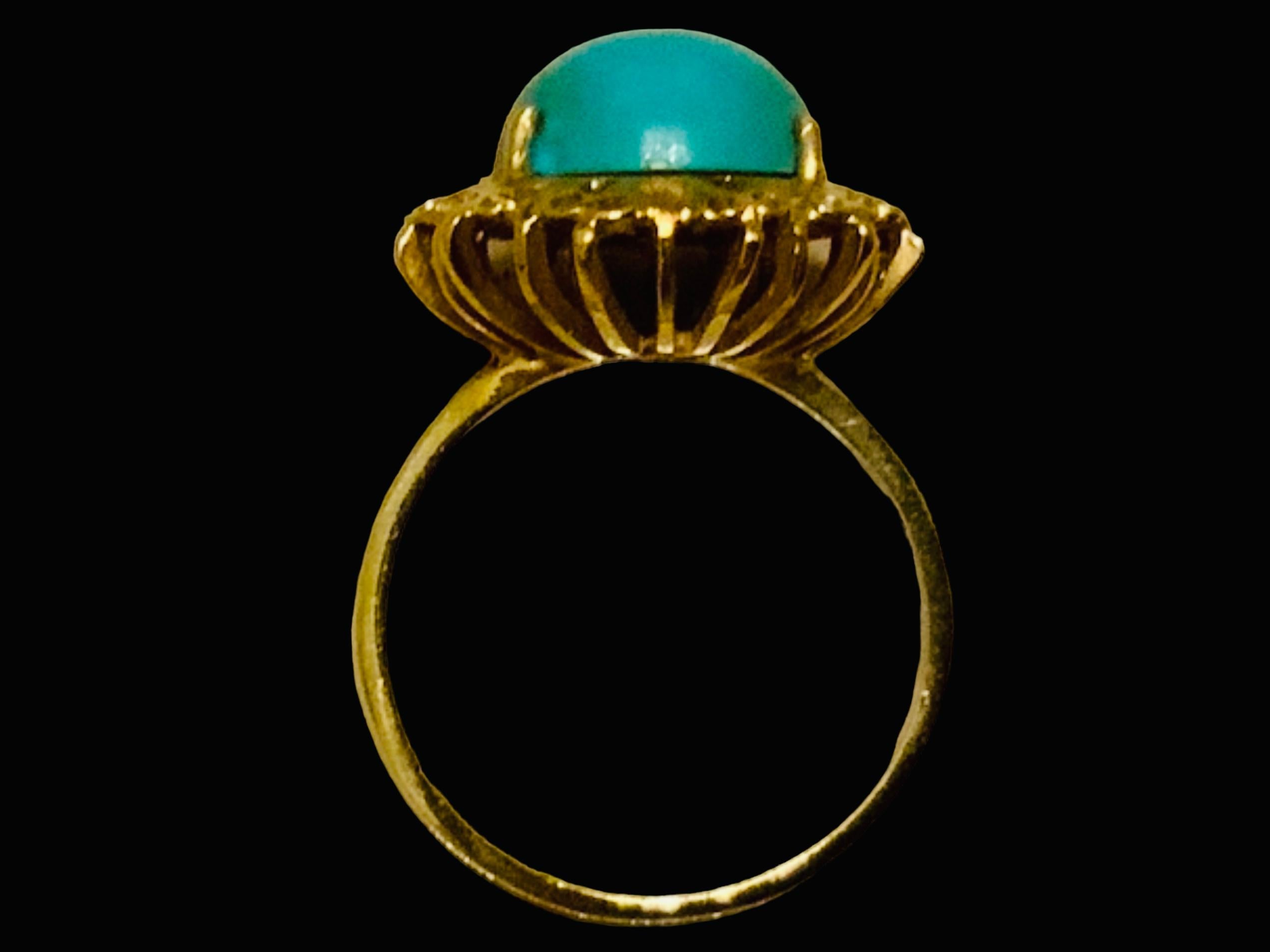 This is an Italian 18K yellow gold and Turquoise cocktail ring. It depicts an elongated oblong shaped cabochon Turquoise stone mounted in gold prong setting and surrounded by a gold wreath made of a garland of tiny bows. The Turquoise’s width and