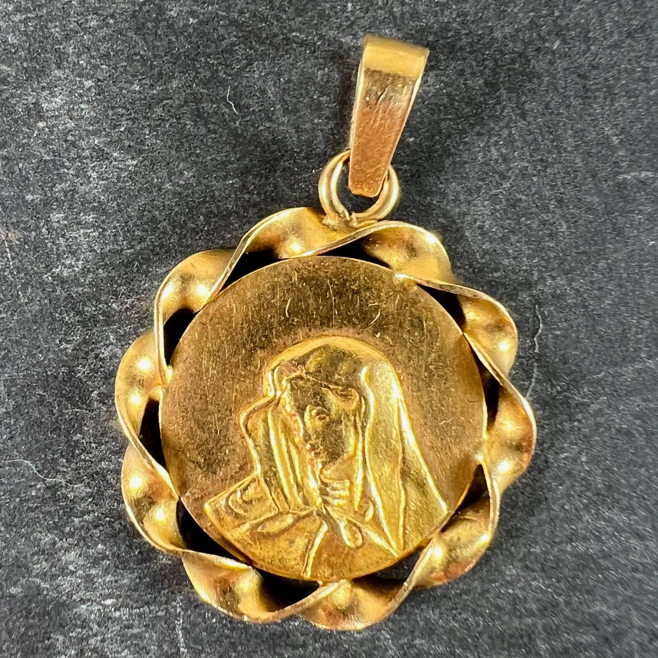 An Italian 18 karat (18K) yellow gold round medal pendant designed as a medal depicting the Virgin Mary. Stamped with 750 for 18 karat gold with marks for Italian manufacture. 

Dimensions: 2.4 x 2.1 x 0.17 cm (not including jump ring)
Weight: 2.72
