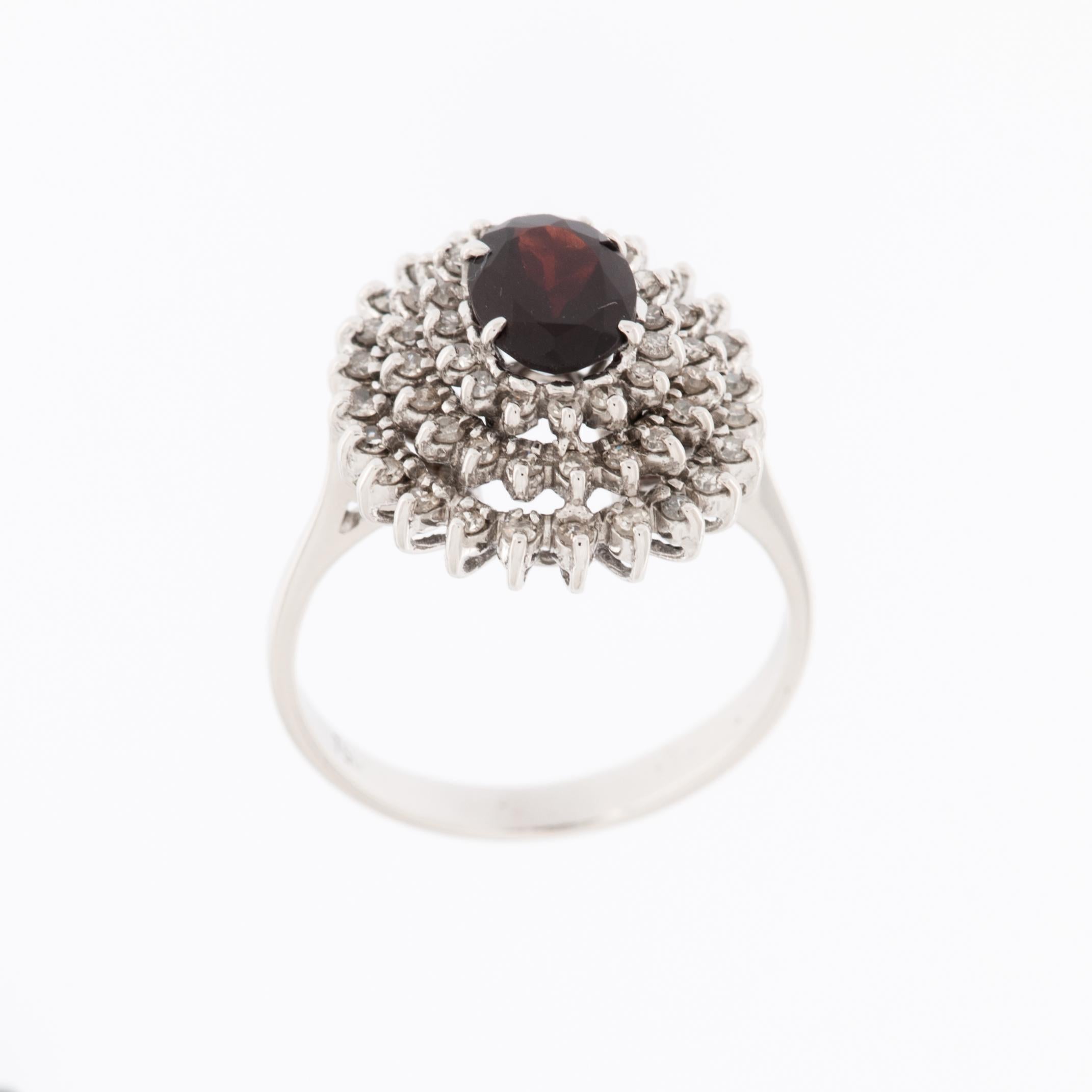 The Italian 18kt White Gold Cocktail Ring with Diamonds and Garnet entourage setting is a stunning and luxurious piece of jewelry. 

This ring is crafted from 18-karat white gold, which is known for its lustrous and durable properties. White gold