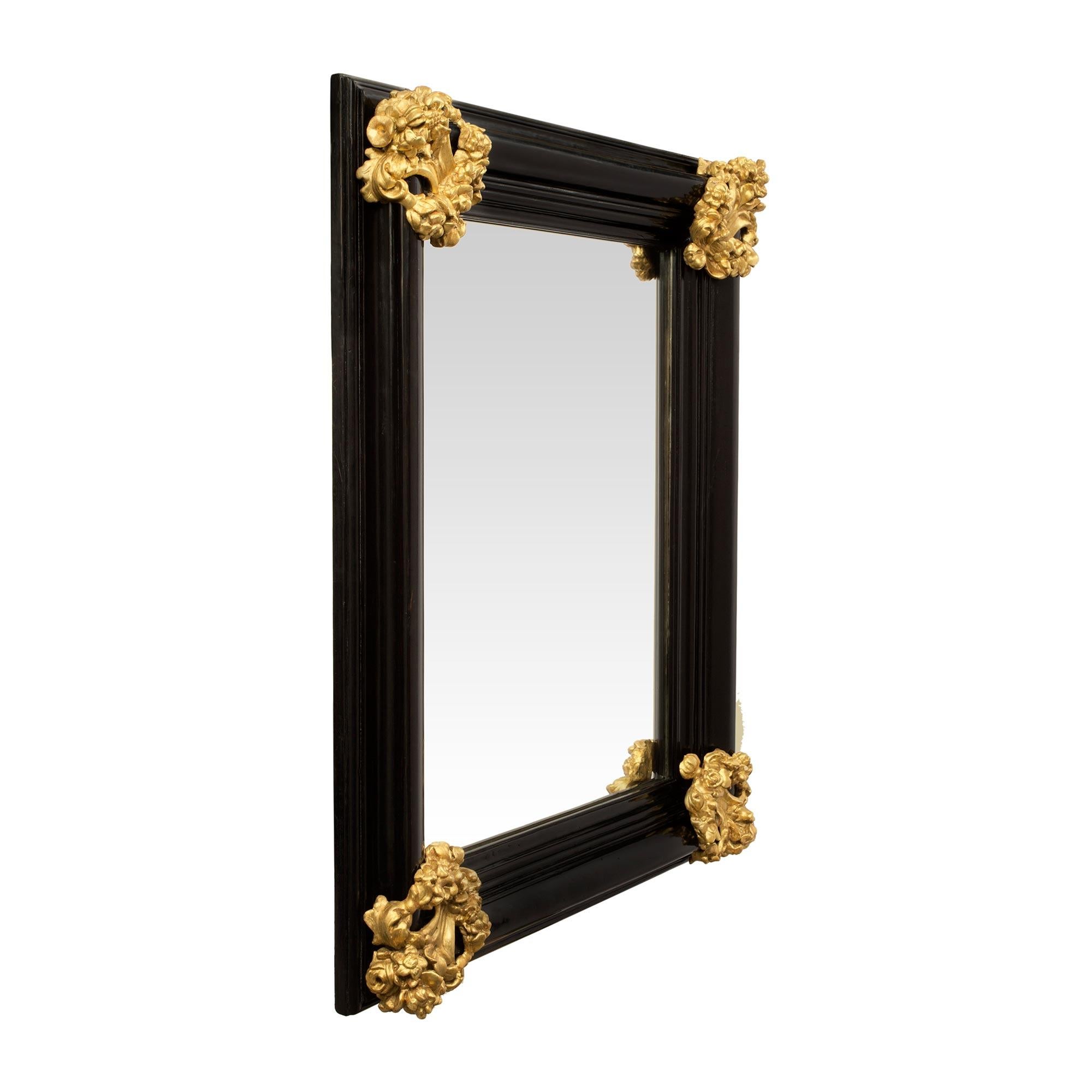 A most attractive Italian 18th century Baroque period Florentine rectangular mirror in ebony and giltwood. The ebony frame with a handsome mottled design has a very decorative and richly carved giltwood reserve at each corner. The pierced reserves