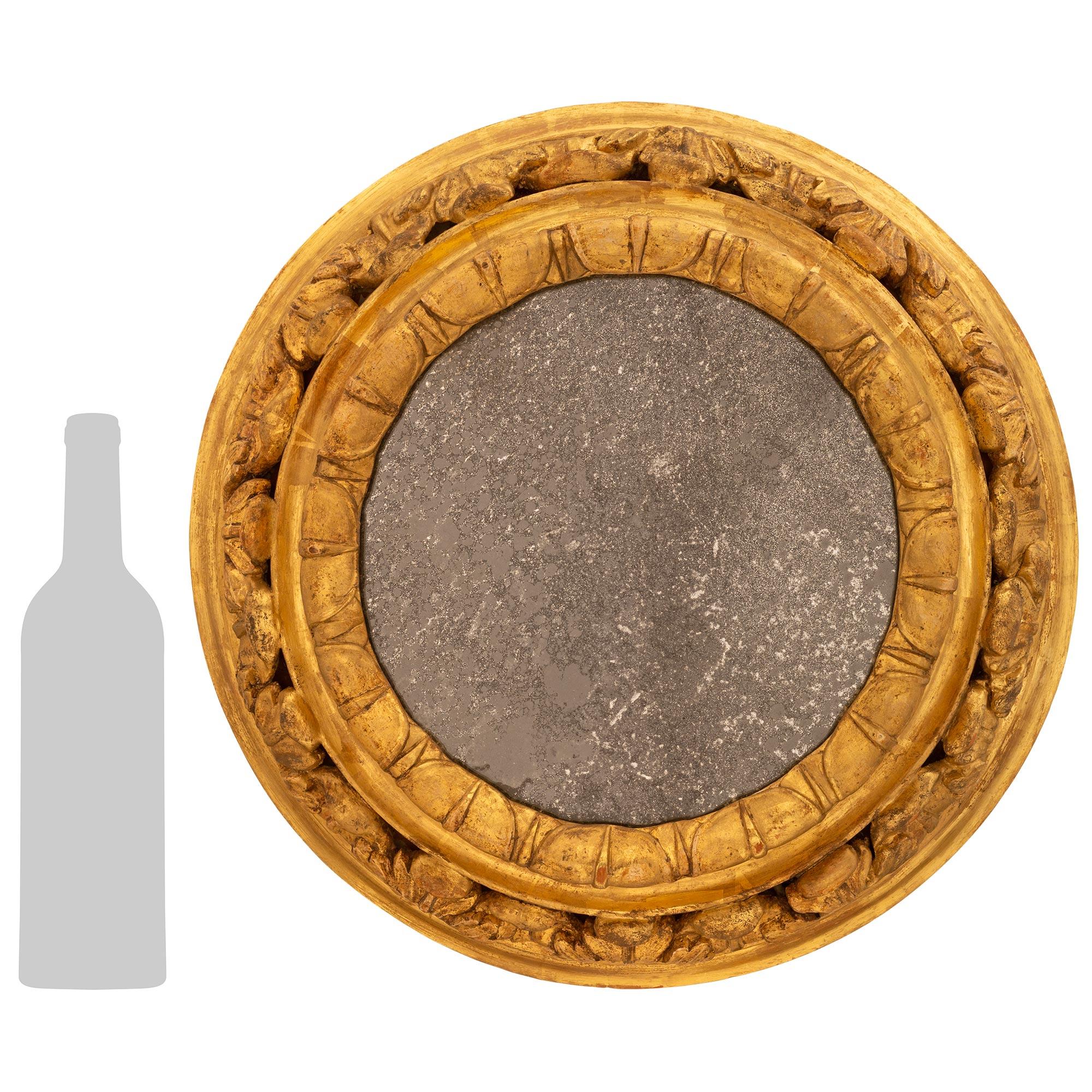 An attractive and most decorative Italian 18th century Baroque period Giltwood mirror. This wonderful circular mirror contains its original mirror plate while the inner frame obtains a beautiful Coeur-de-Rai carved patterned band. The outer band of