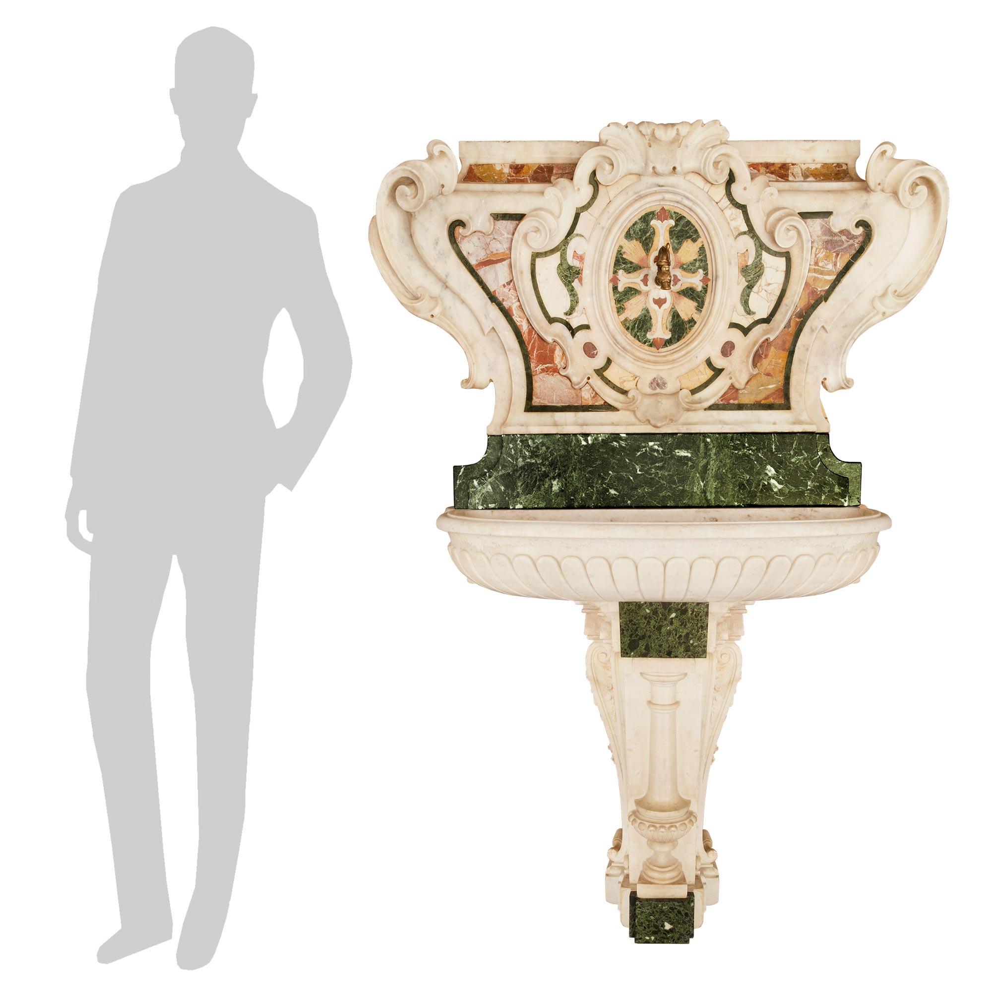 A most impressive and extremely decorative Italian 18th-century Baroque period marble fountain. The marble fountain is raised by a white Carrara marble and Vert De Patricia marble base. The base is with a front half round circular column flanked by