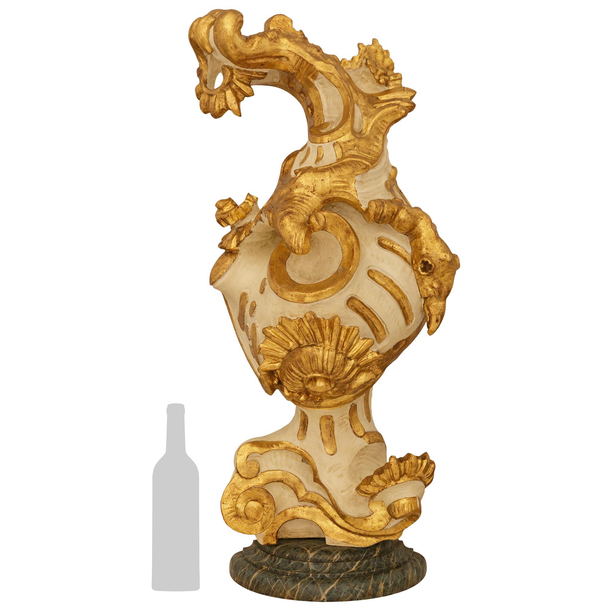 An impressive and most attractive Italian early 18th century Baroque Period patinated Wood and Giltwood Conch Shell architectural element. This most decorative carved Giltwood Conch Shell is raised on a faux green veined marble demi lune socle,