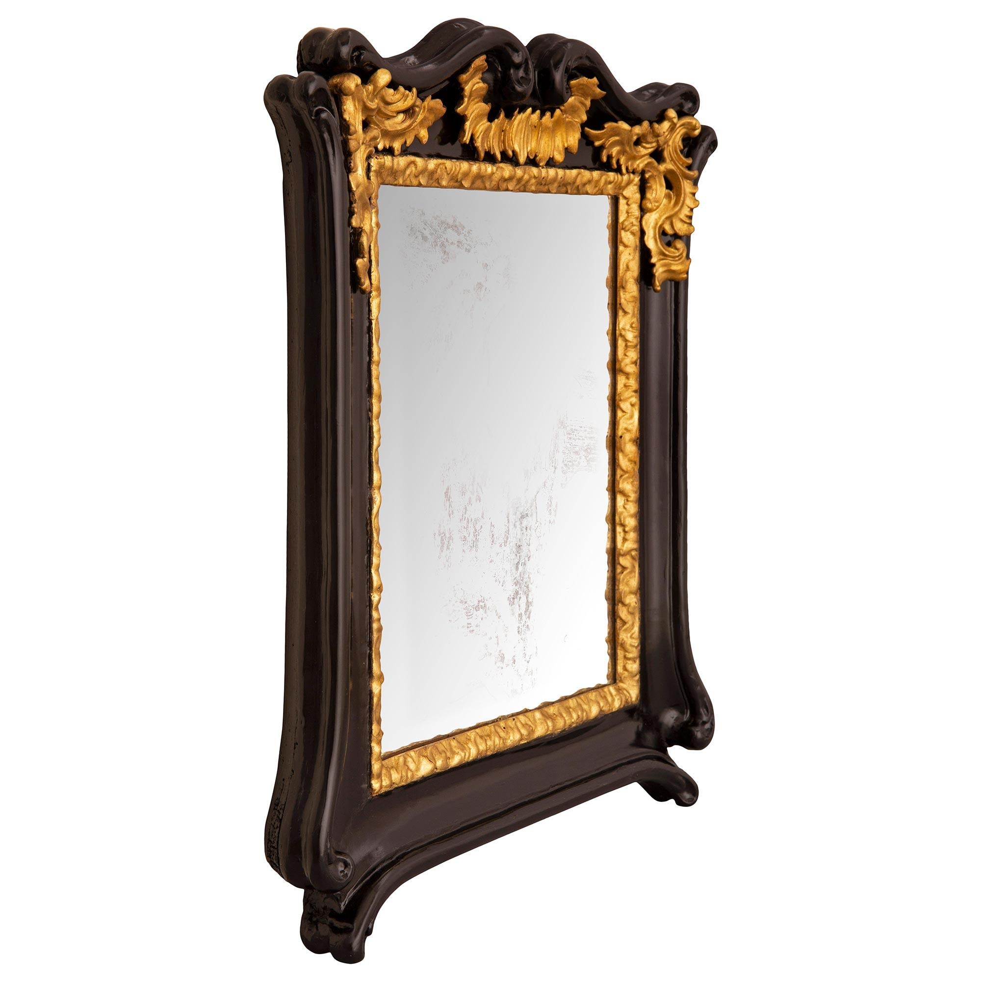 A fabulous and most decorative Italian 18th century Baroque st. ebonized Fruitwood and giltwood mirror. The mirror retains its original mirror plate set within an elegant finely carved giltwood border. The ebonized Fruitwood frame displays an