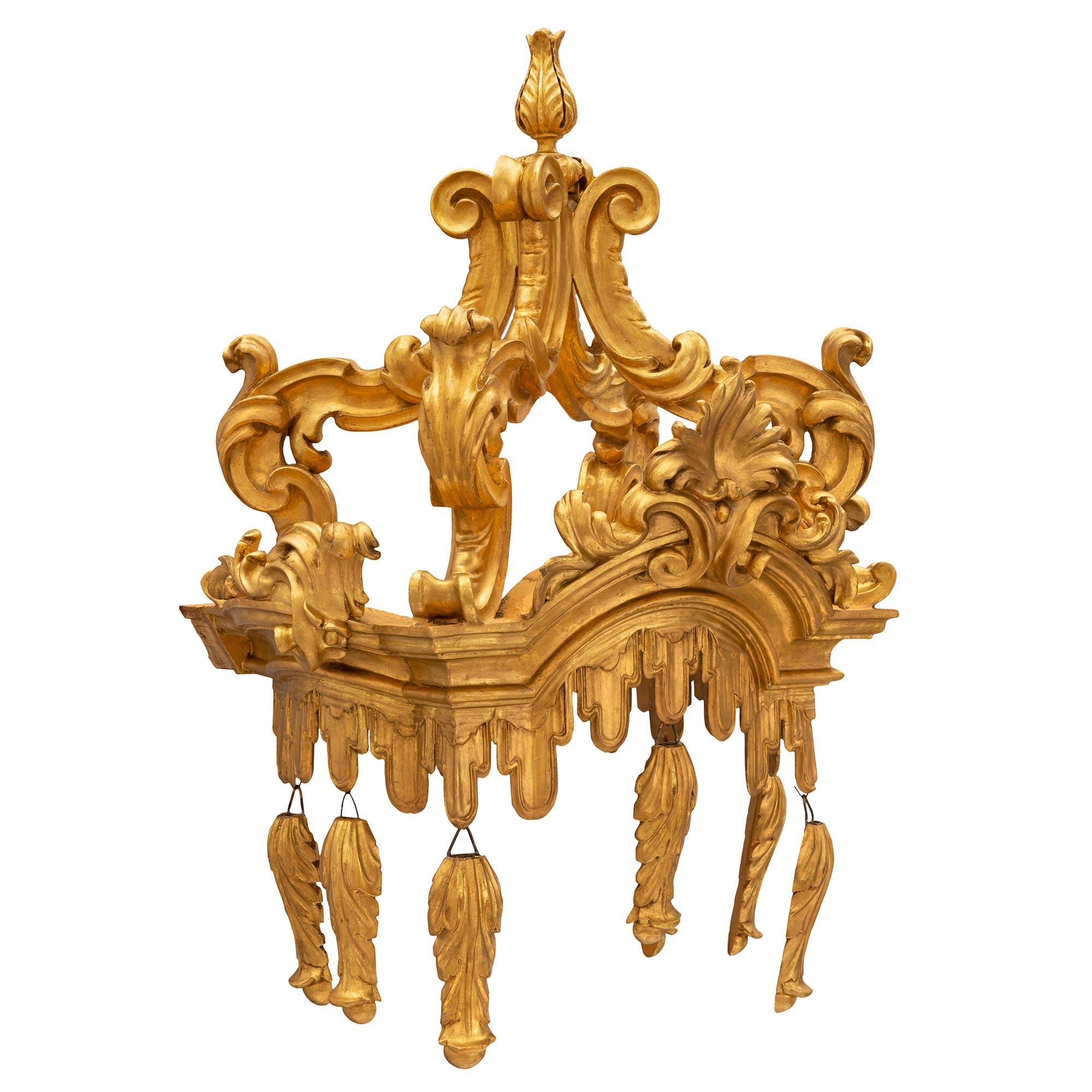 A unique and most decorative Italian 18th century Baroque st. giltwood canopy. The beautiful canopy displays richly carved giltwood acanthus leaf pendants below a draped fabric like garland design that extends along the border. At the center is a