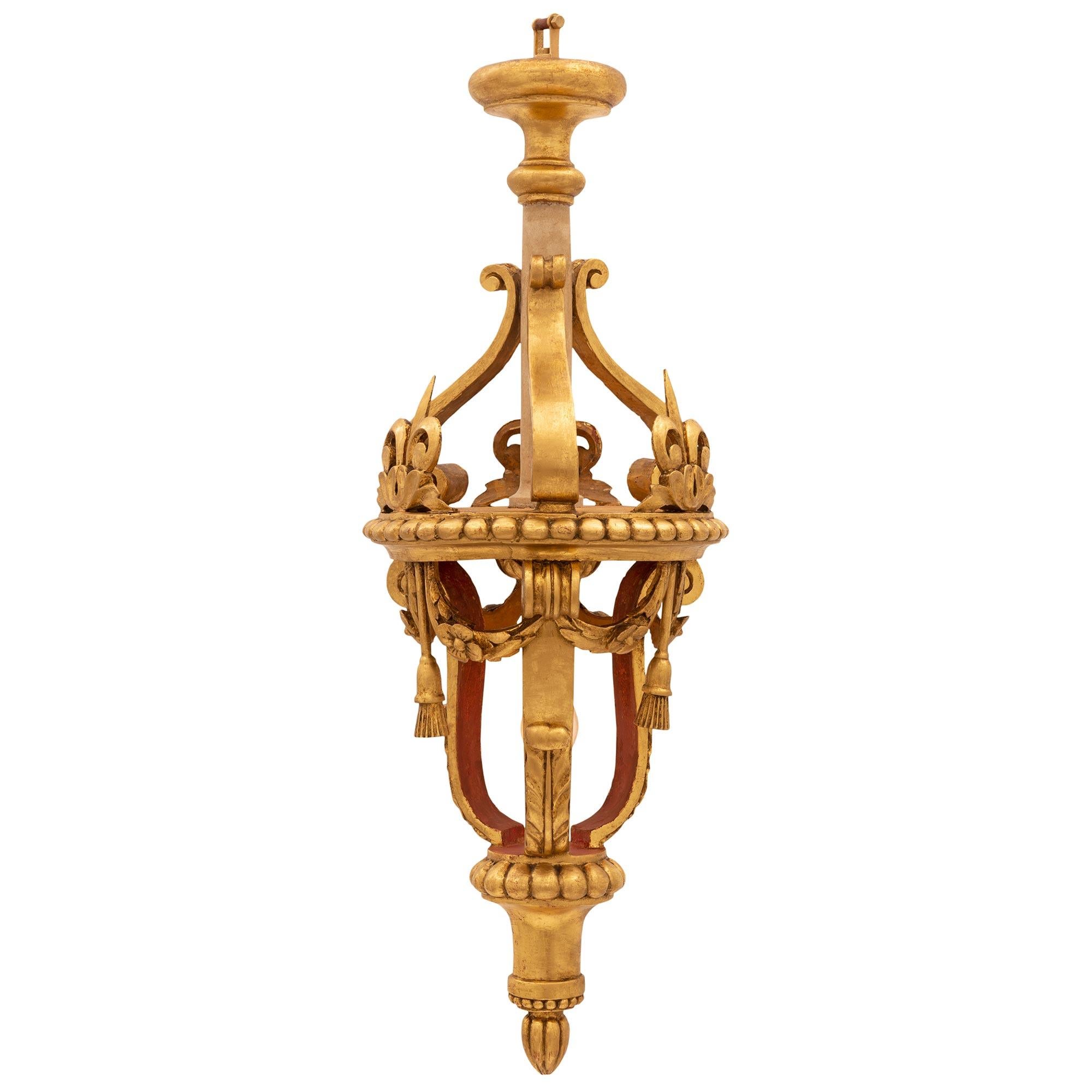 A lovely Italian 18th century Baroque st. giltwood lantern. The lantern is centered by a charming bottom foliate finial below an elegantly curved support and wrap around reeded band. Three scrolled supports lead upwards adorned with richly carved