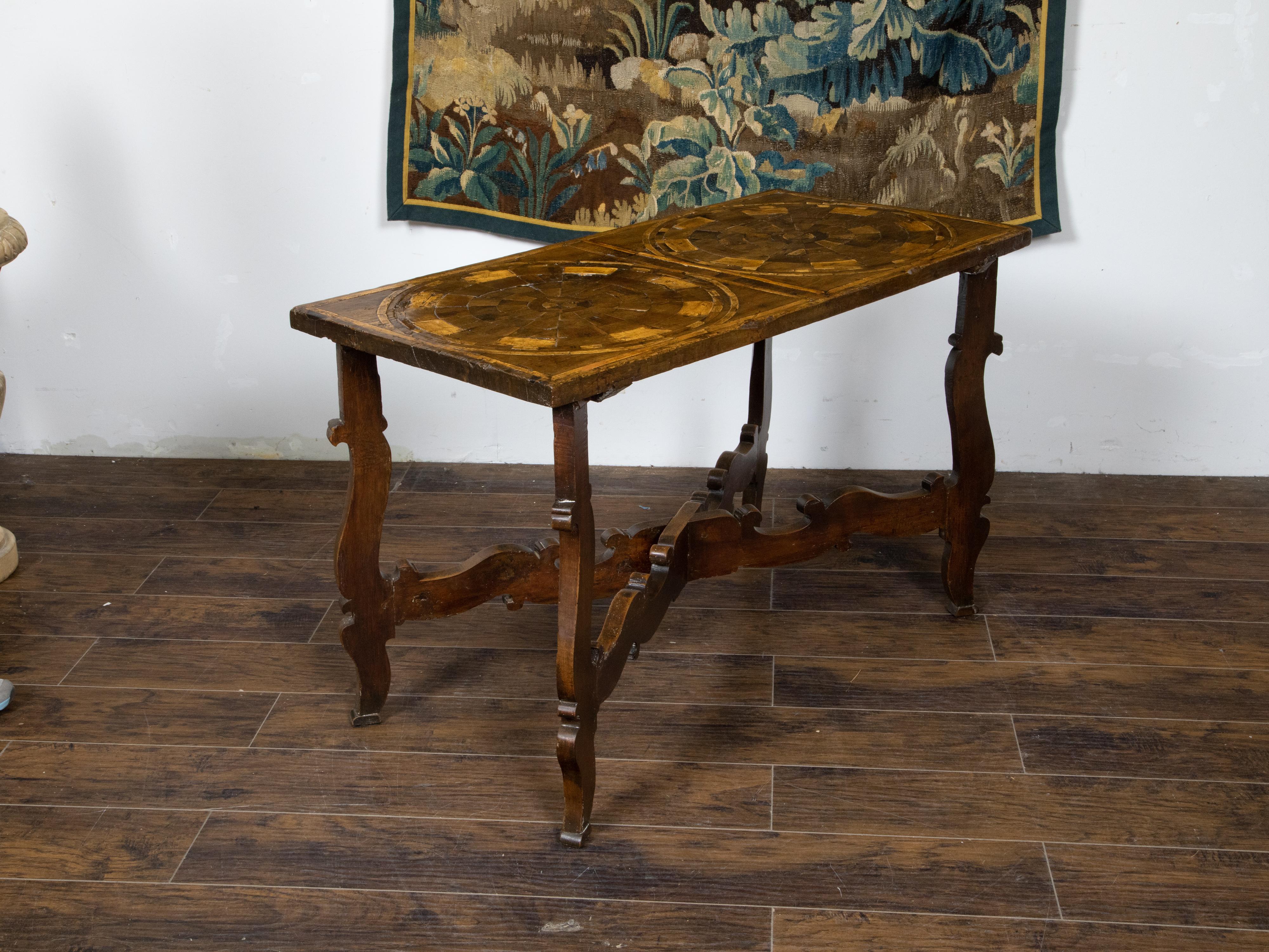 An Italian Baroque style walnut console table from the 18th century, with marquetry geometric top and carved base. Created in Italy during the 18th century, this walnut table draws our immediate attention with its rectangular top adorned with an