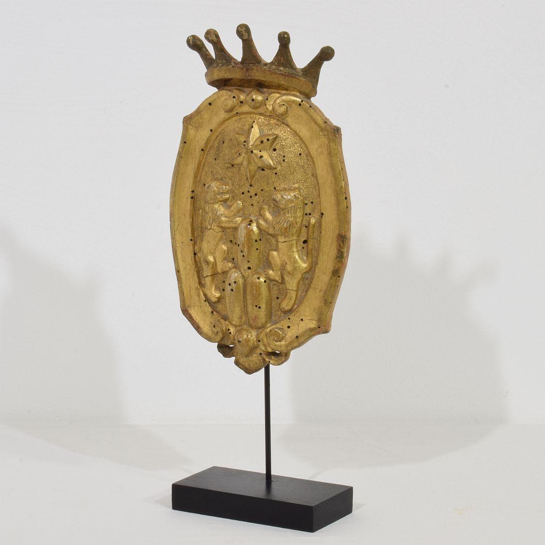 Wonderful handcarved wooden coat of arms with its original gilding, Italy, circa 1750. 
Weathered, small losses and old repair. Treated against wood worm. Measurement includes the base.