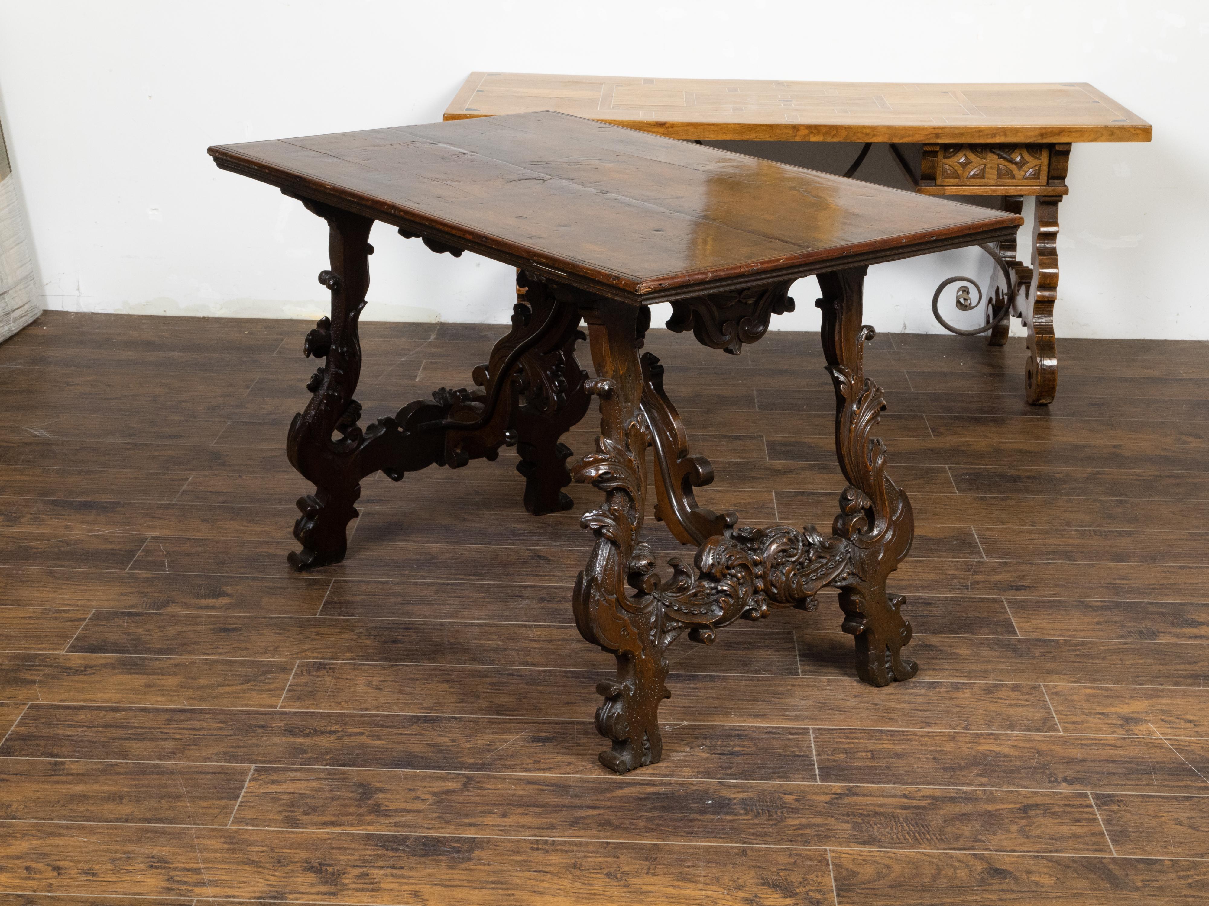 An Italian Baroque style walnut Fratino console table from the 18th century, with carved lyre-shaped trestle base, scrolling foliage motifs, dolphin feet and dark brown patina. Created in Italy during the lively 18th century, this Baroque walnut