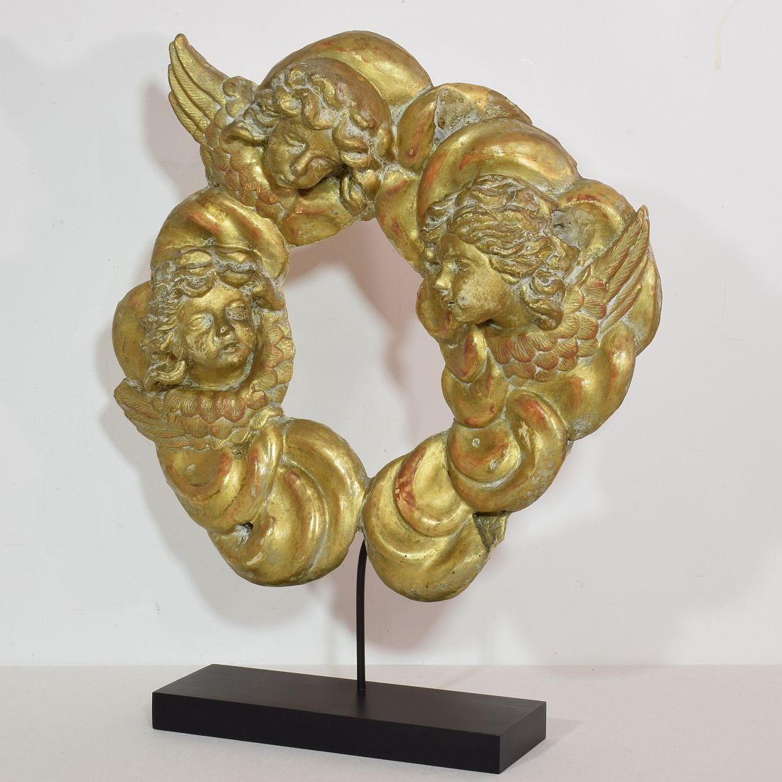 Wonderful hand carved wreath of baroque clouds with 3 winged angel heads.
Italy, circa 1750. Gilt and gilt paint visible
Weathered and small losses. Now placed on a pedestal but can also be hanged at a wall.
Measurement here below inclusive the