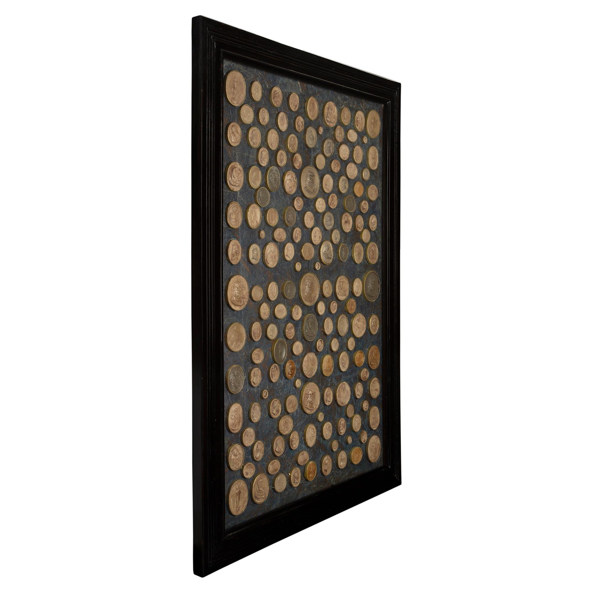 A very attractive and extremely decorative Italian 18th Century collection of wax reliefs. The seals are framed within a period ebonized fruitwood mottled rectangular frame. The extensive collection of various sized busts of philosophers and