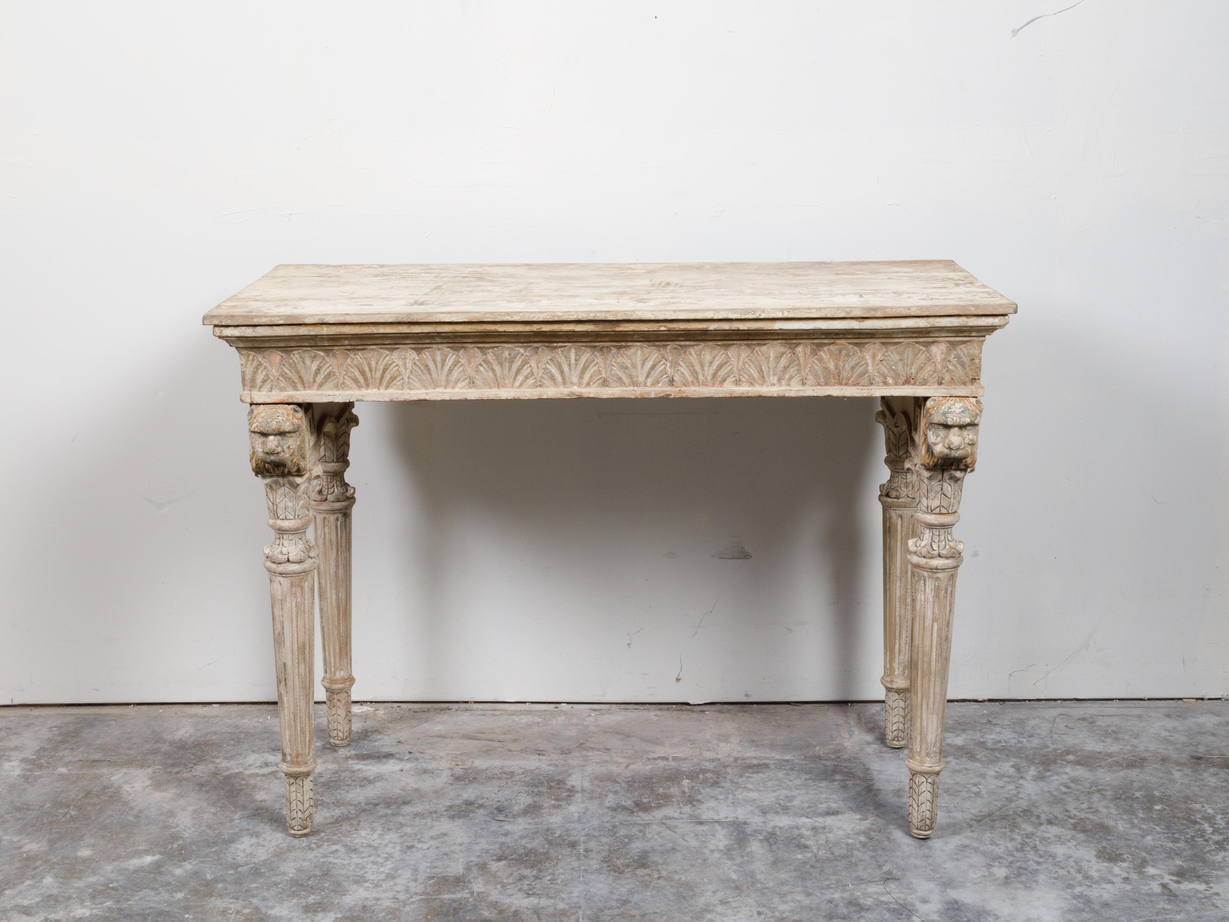 An Italian Neoclassical console table from the 18th century, with carved animals, fluted legs and distressed patina. Created in Italy during the 18th century, this console table features a rectangular top with nice aging, sitting above an apron
