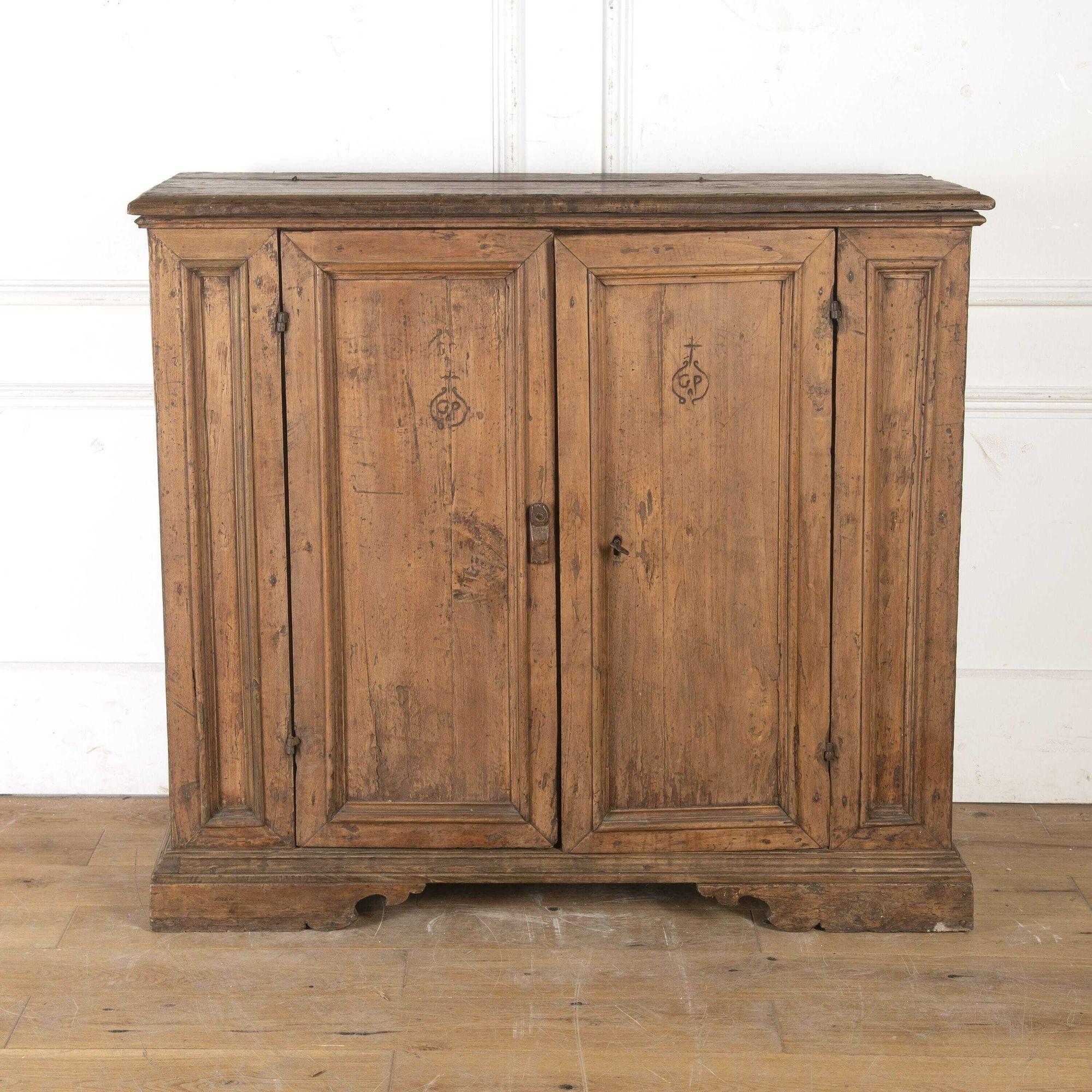 Wonderful 18th Century cupboard from a Tuscan convent. 
This fascinating fruitwood cupboard has low proportions with two central doors flanked by panelled sections. The doors each bear a hand-carved crucifix and the letters G.P. 
Inside are two