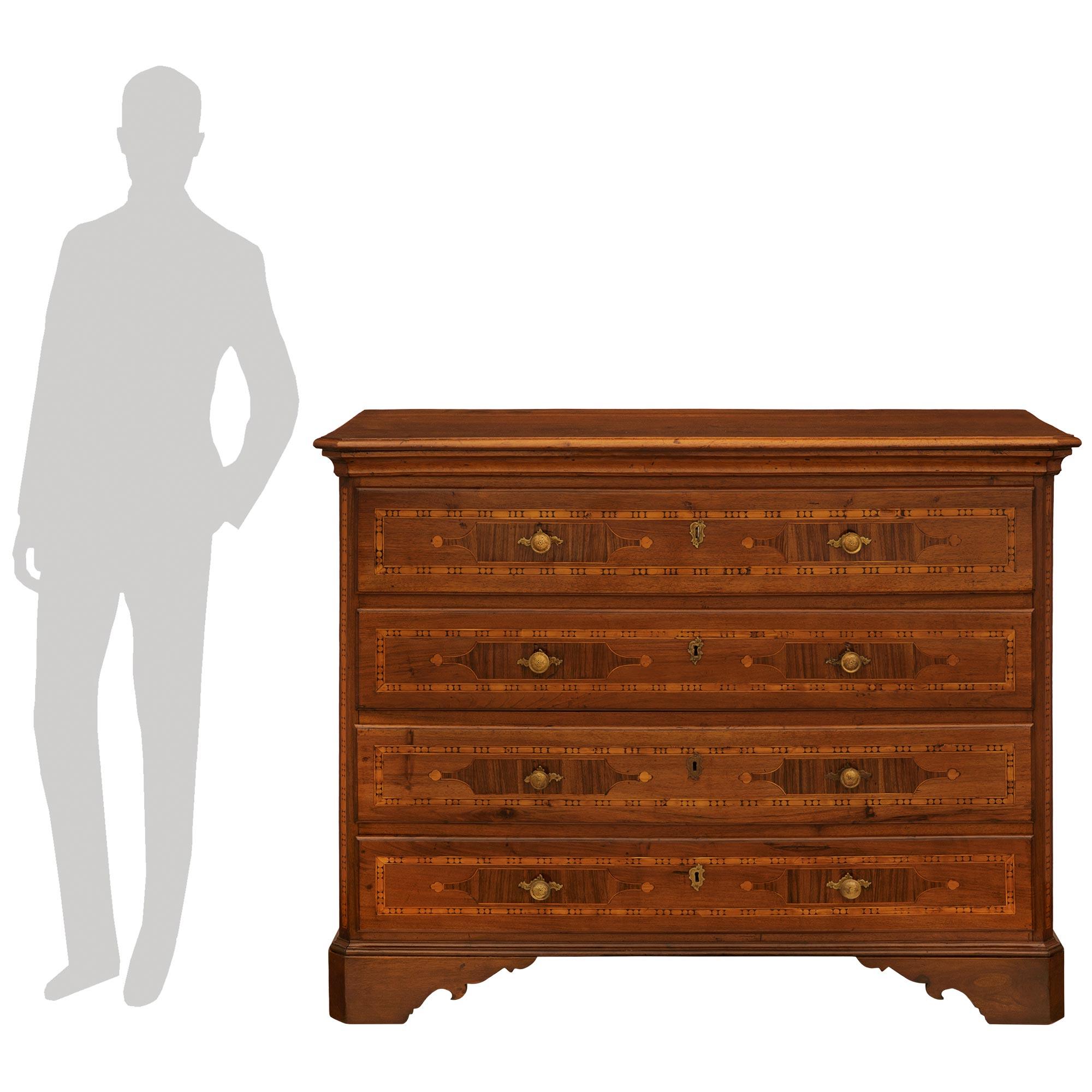 A handsome and most decorative Italian 18th century Louis XVI st. Pine, Walnut and Brass chest. The wonderful four drawer chest is raised on scalloped supports below a mottled straight frieze. Each of the four drawers retain their original Brass