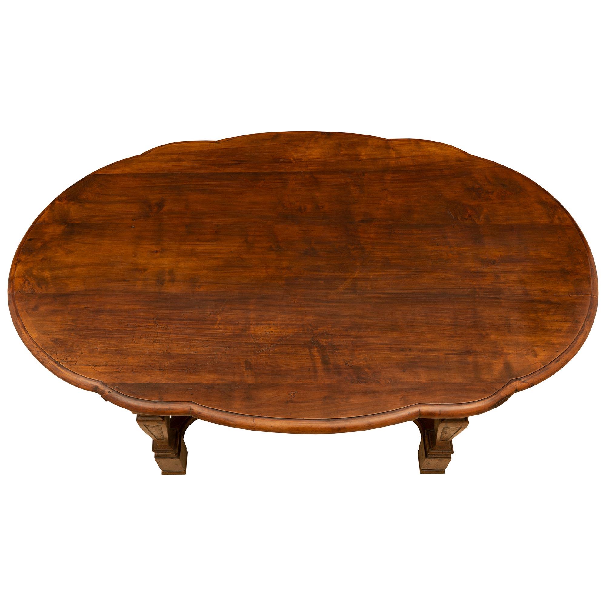 A sensational and unusual mid 18th century country Italian walnut oval center/dining table. The table is raised by four baluster shaped carved legs joined by an X curved moulded stretcher with a central oval. At each side is a serpentine shaped