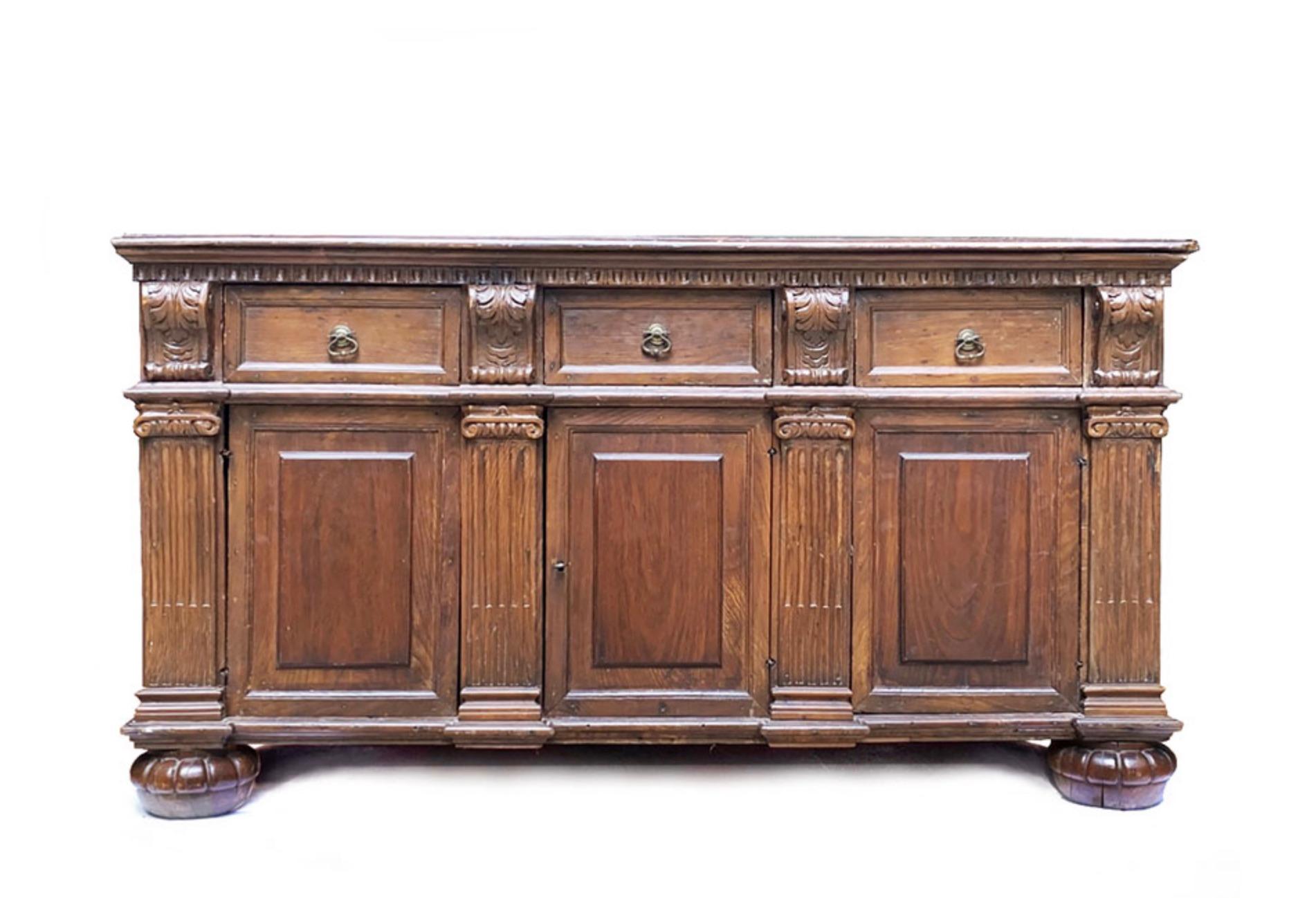 A magnificent 18th-century Italian credenza, masterfully handcrafted from rich hardwood with a deep, warm patina. This stately piece exemplifies classical Italian furniture design, featuring intricate carved details, fluted pilasters, and elegant