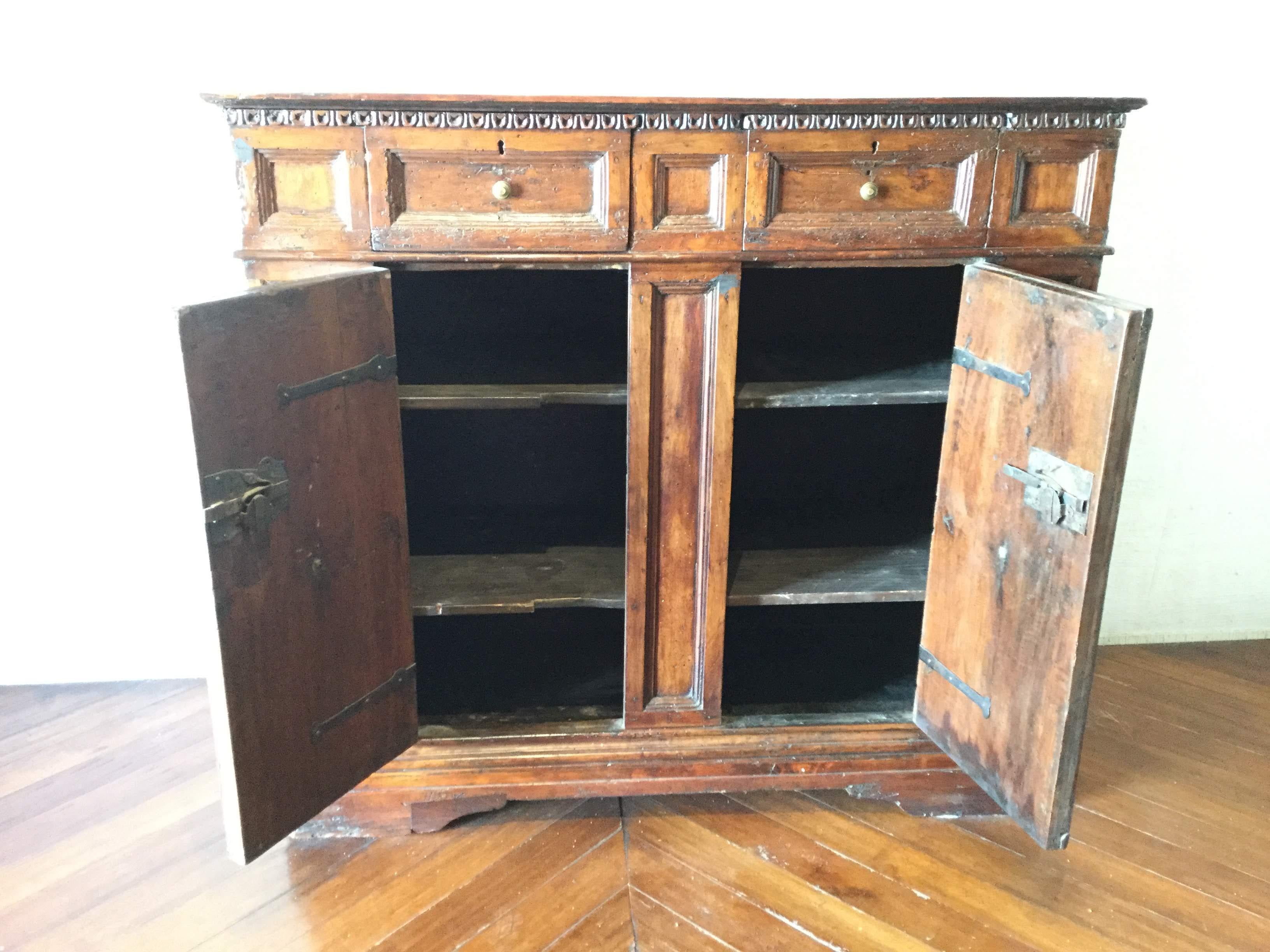 Walnut wood. Of a dark patina with a diamond molding work in the two front doors, two front central drawers and two interior shelves. Great presence and condition standing on original “Piedi a mensola”.
  