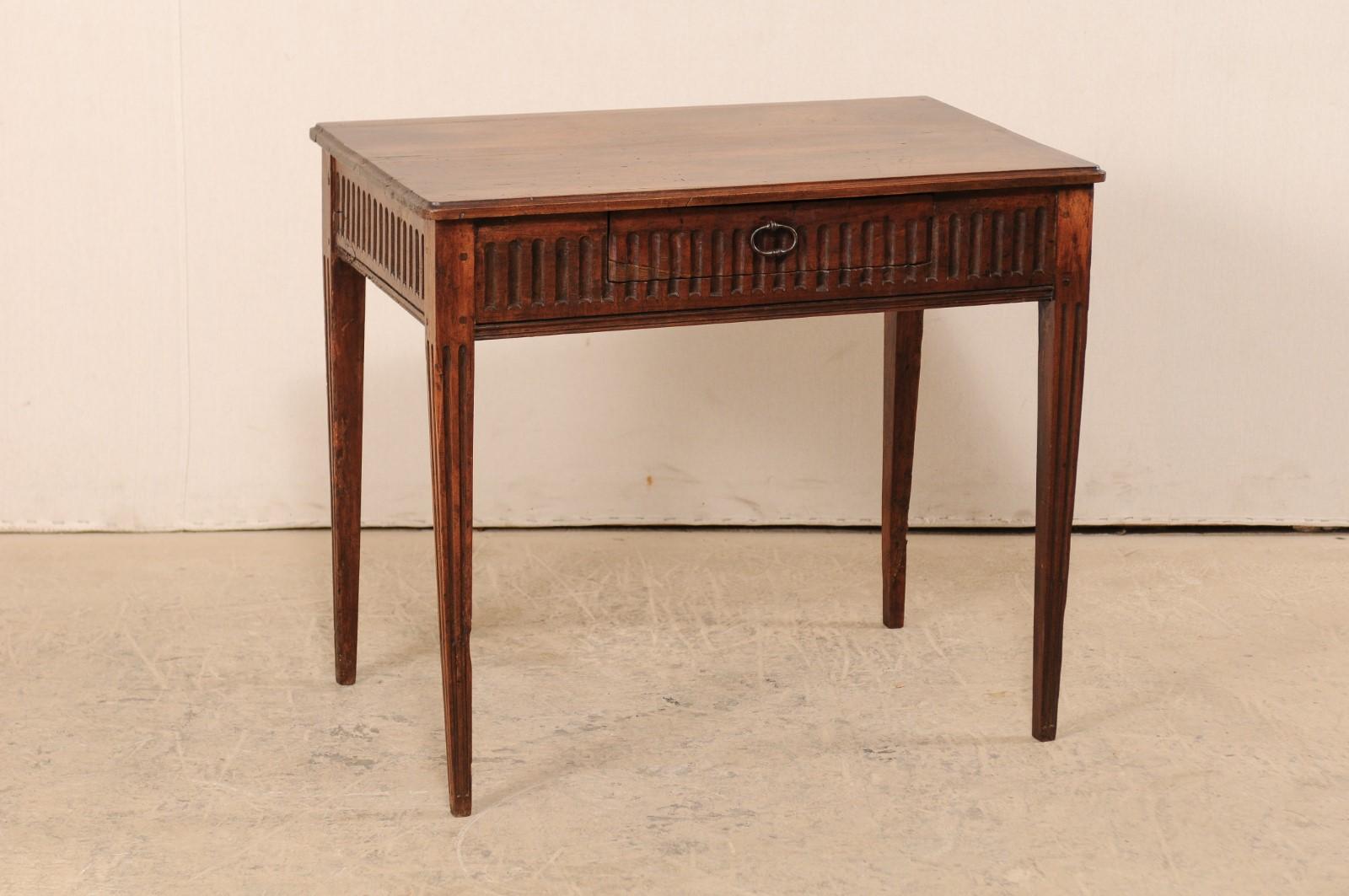 An Italian carved wood occasional table with single drawer from the 18th century. This antique table from Italy features beautifully carved fluted details about all sides of the apron, and down each of the four legs. The rectangular-shaped top has