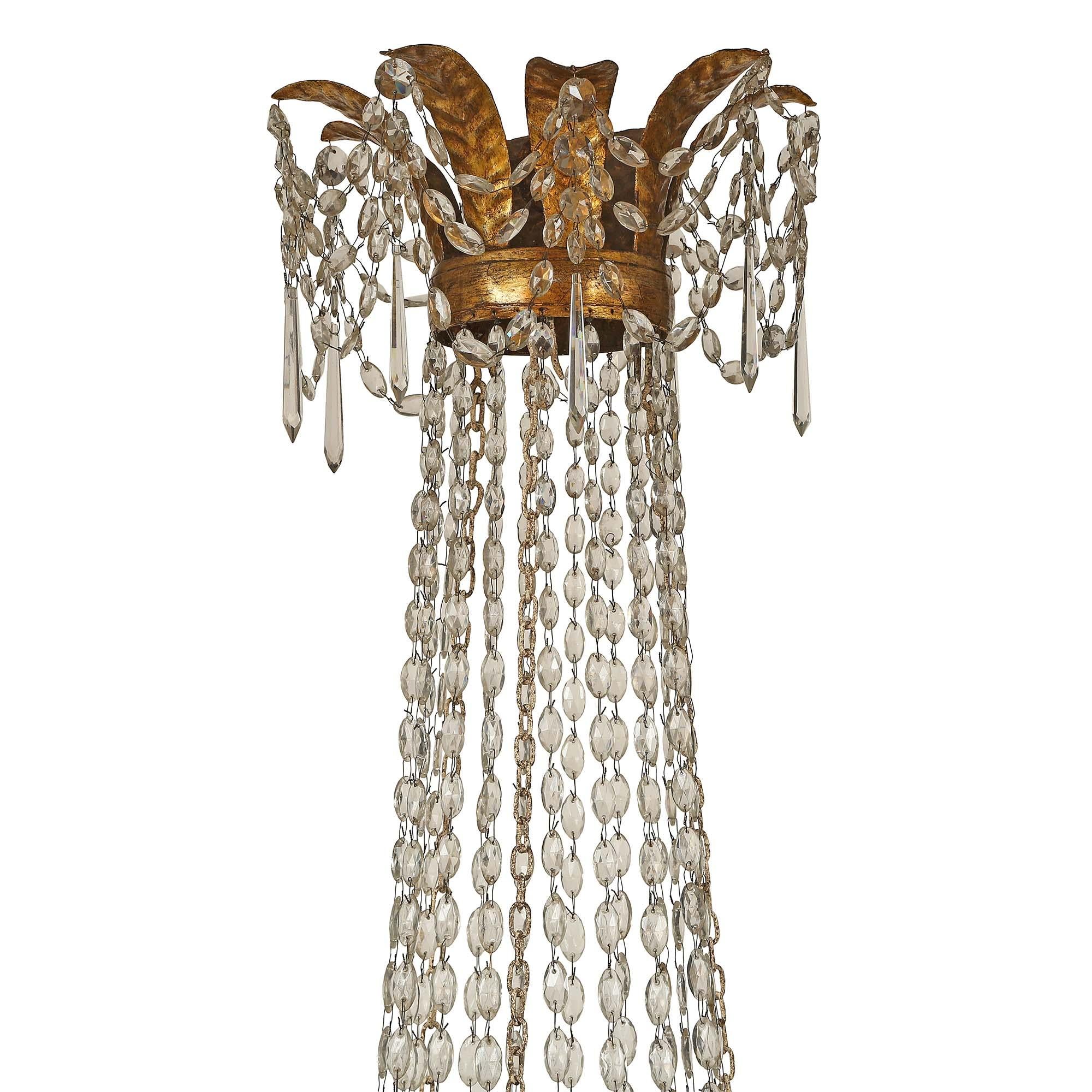 A most unique and extremely decorative Italian 18th century gilt metal, gilt wood and patinated wood sixteen light chandelier. The chandelier is centered by a bottom gilt metal band with cut crystal pendants. Leading up finely carved giltwood and