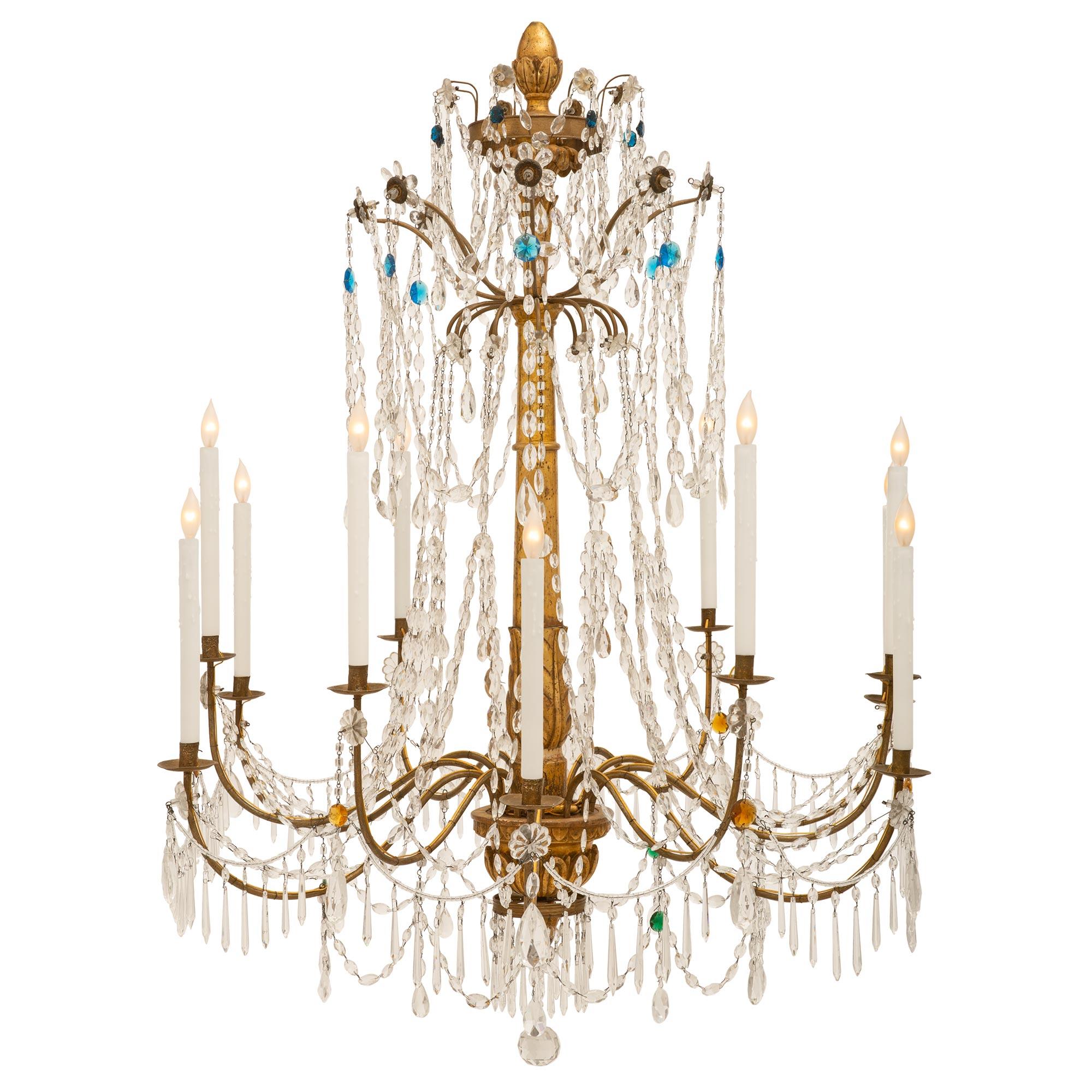 Superbe lustre Genovese à douze lumières en bois doré et cristal du 18e siècle. Les bras en fer doré à volutes sont magnifiquement décorés de guirlandes et de pendentifs en cristal, avec une boule de cristal centrale. Le fut central sculpté est orné