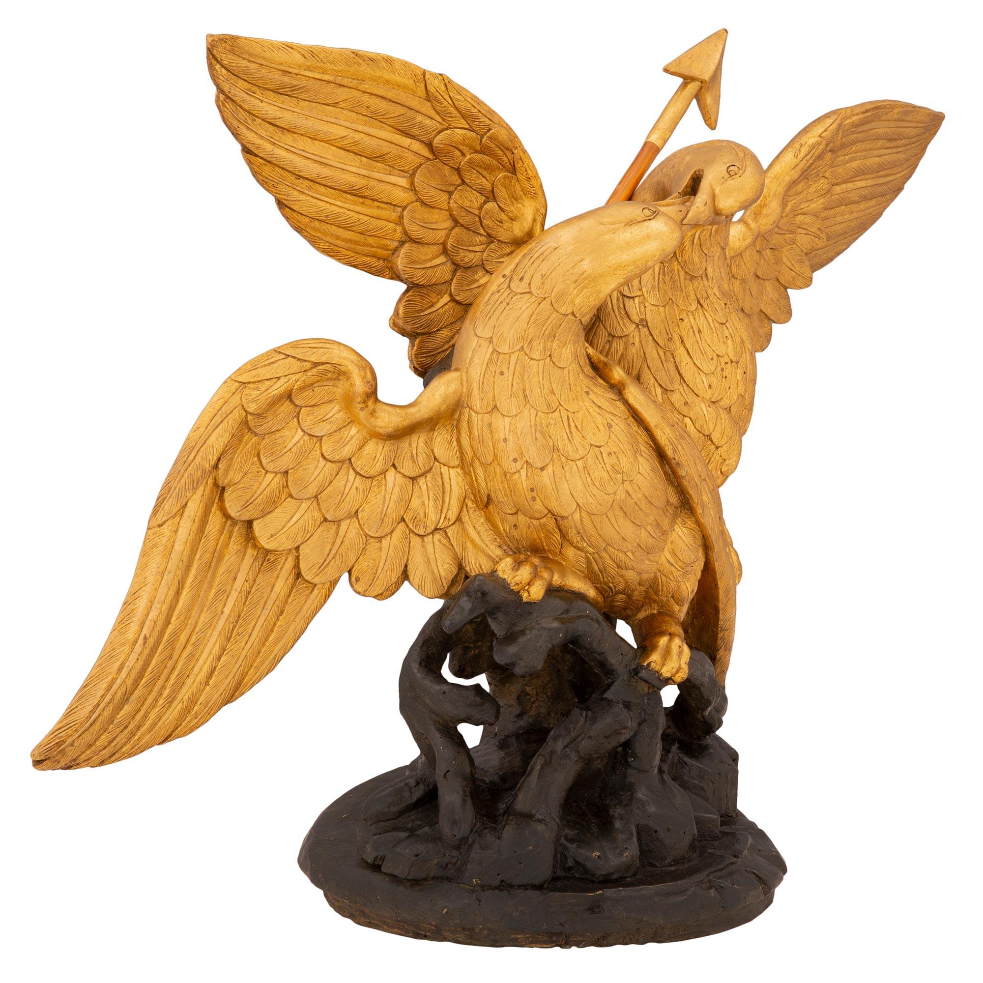 A striking Italian 18th century giltwood and polychrome statue of two eagles. The statue is raised by a most decorative polychrome ground and branch like designed base. Above are two striking and richly carved eagles engaged in a battle over their