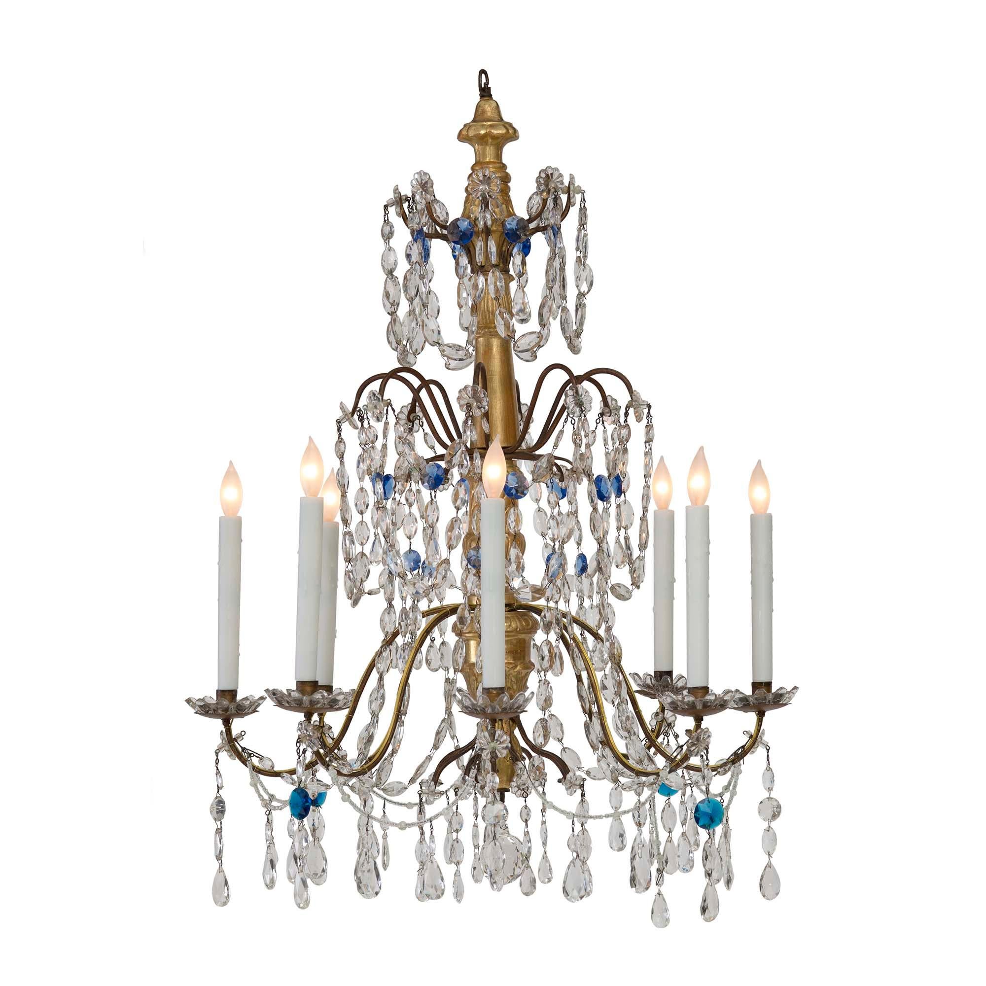 A charming Italian 18th century giltwood, gilt metal and glass eight light chandelier. The chandelier with eight electrified S scrolled metal arms leading to giltwood candle cups and ridged patinated metal saucers. The arms are decorated with glass