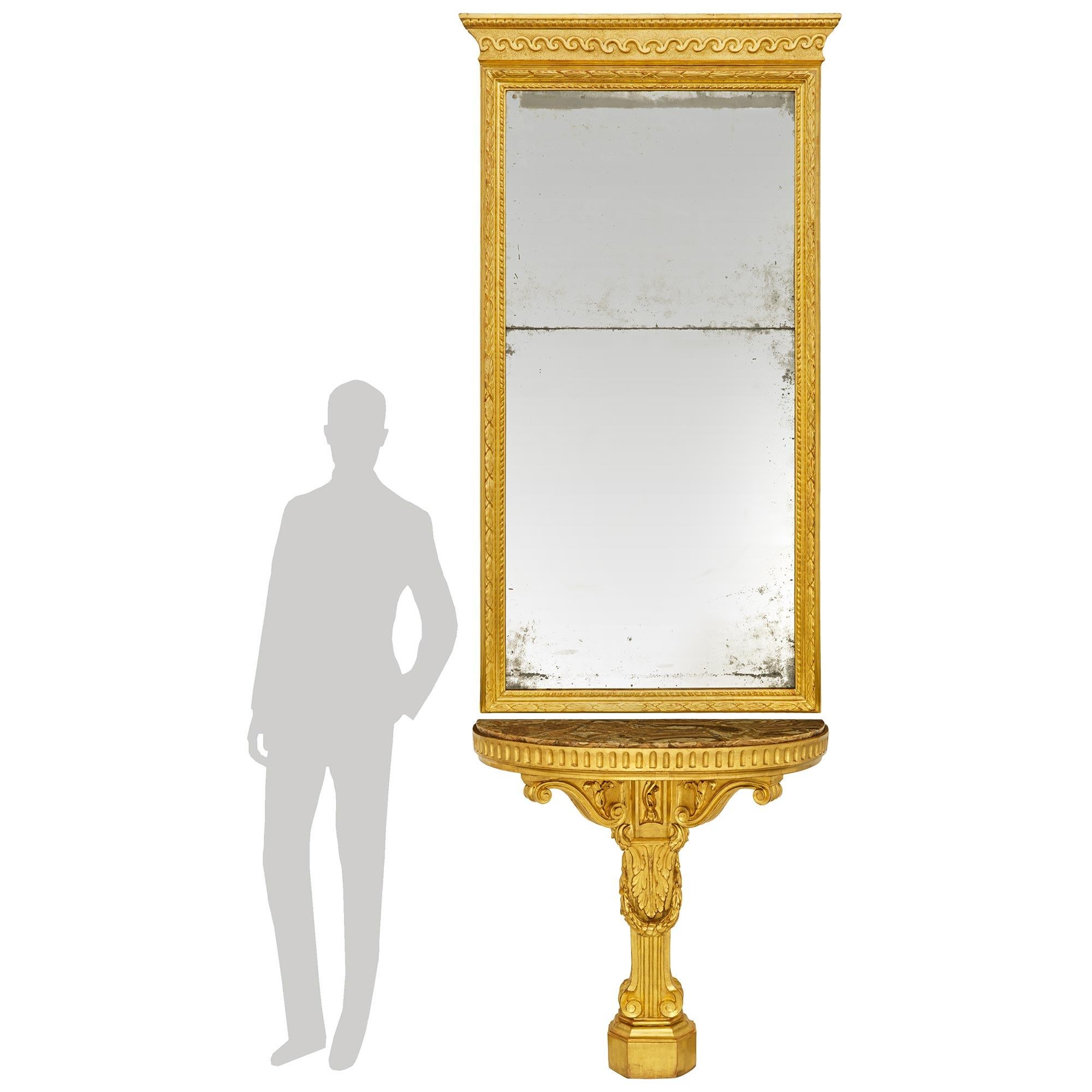An elegant and most decorative Italian mid 18th century Louis XVI Period Giltwood, Mirror and marble console and mirror. This exceptional and palatially scaled matching console and mirror are raised on a single central leg supported on a mottled