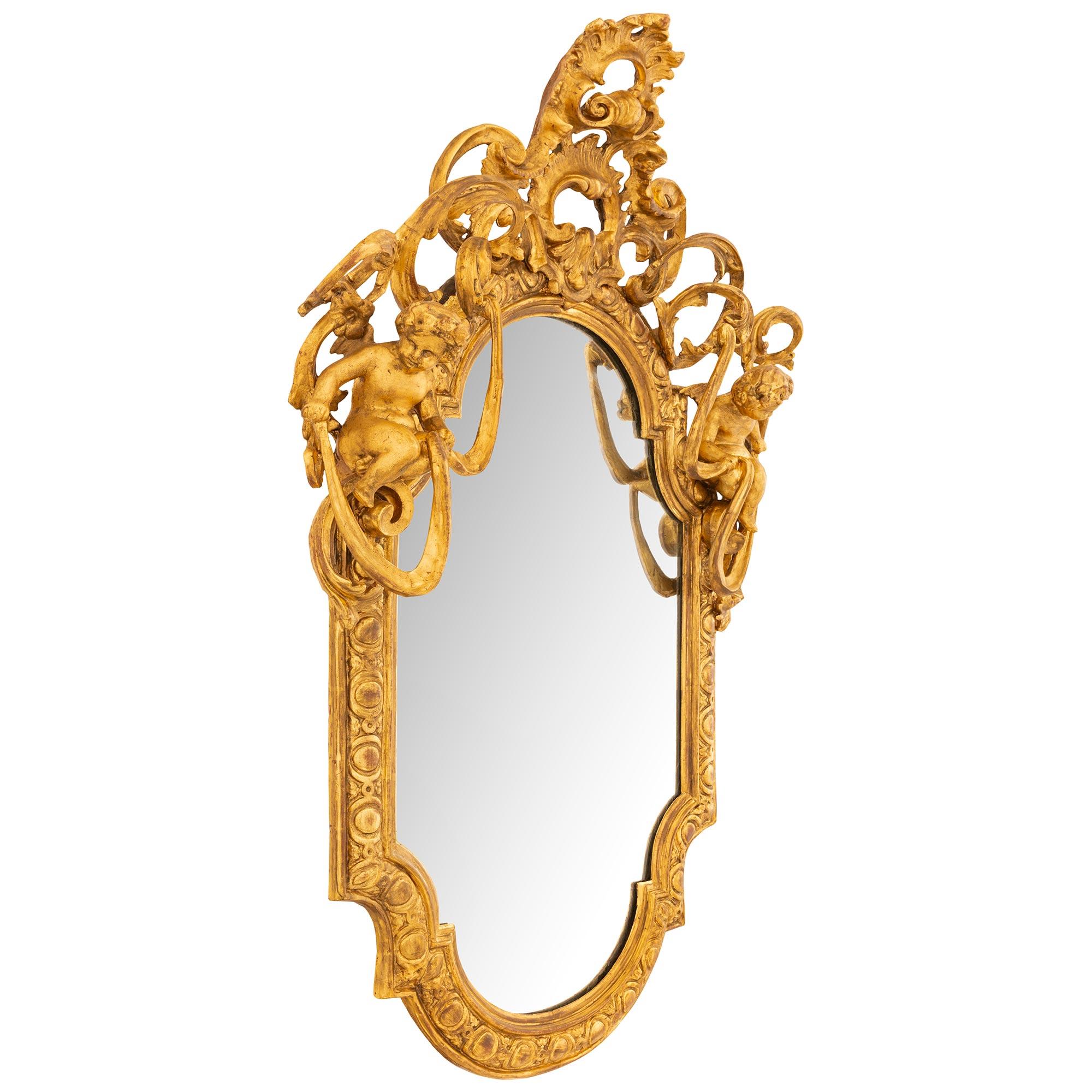 Miroir en bois doré italien du XVIIIe siècle de très grande qualité et d'une grande élégance. Le cadre à cabochon, très attrayant et richement sculpté, présente une coquille centrale supérieure au milieu d'un motif de feuilles d'acanthe à volutes