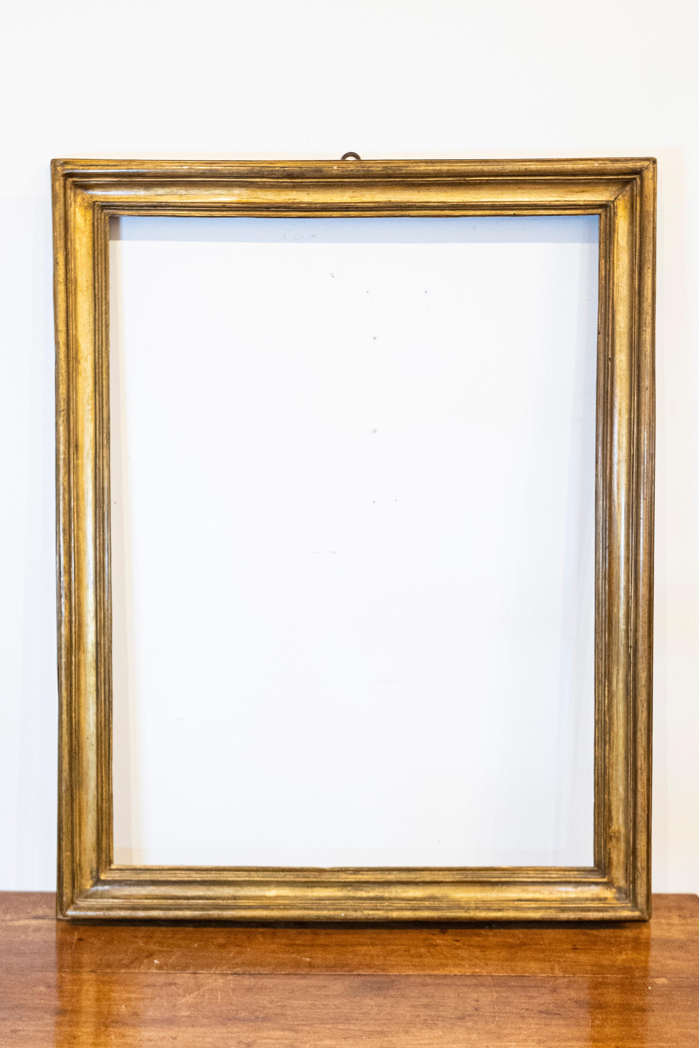 An Italian giltwood frame from the 18th century with rustic character, perfect to house a painting or a picture. This 18th-century Italian giltwood frame embodies a sense of time-worn elegance, its rustic character a testament to the beauty of aged
