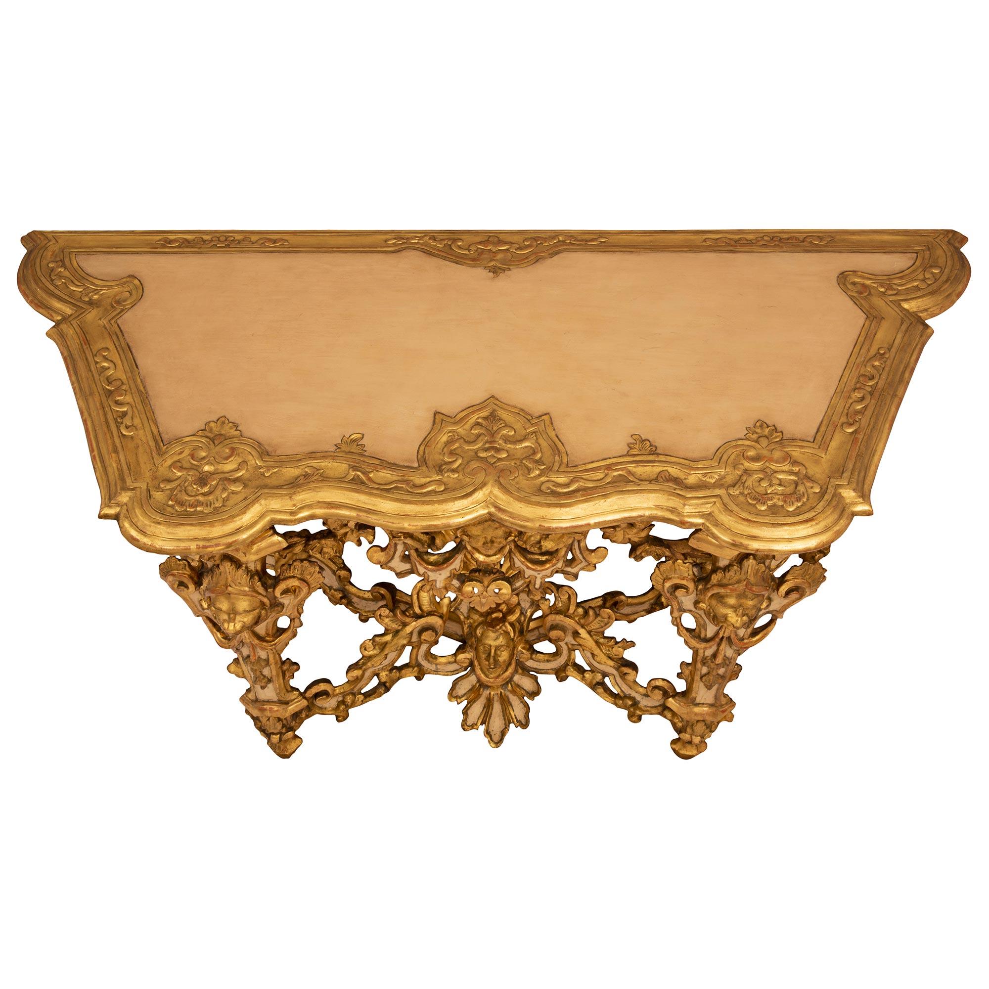 A spectacular Italian 18th century Louis XIV period giltwood and patinated wood Lombardi console. The freestanding console from Lombardi is raised by four most impressive tapered supports with fine topie shaped feet and superb foliate designs with
