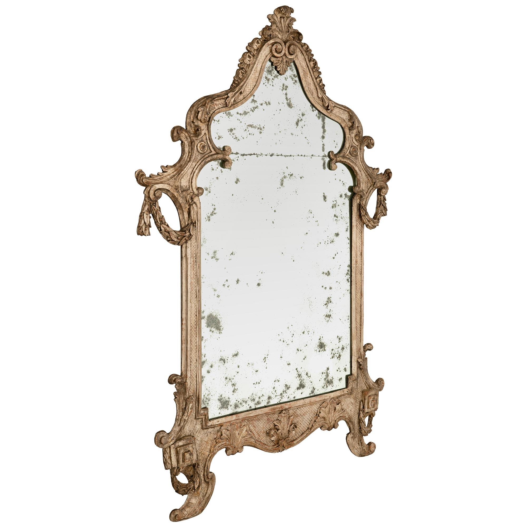 A very attractive Italian 18th century Louis XV period carved mecca mirror. This unique mirror has a lattice designed frame with scrolled feet, Greek key designs,and wreaths at each bottom corner. The scalloped bottom has scrolled edges and large