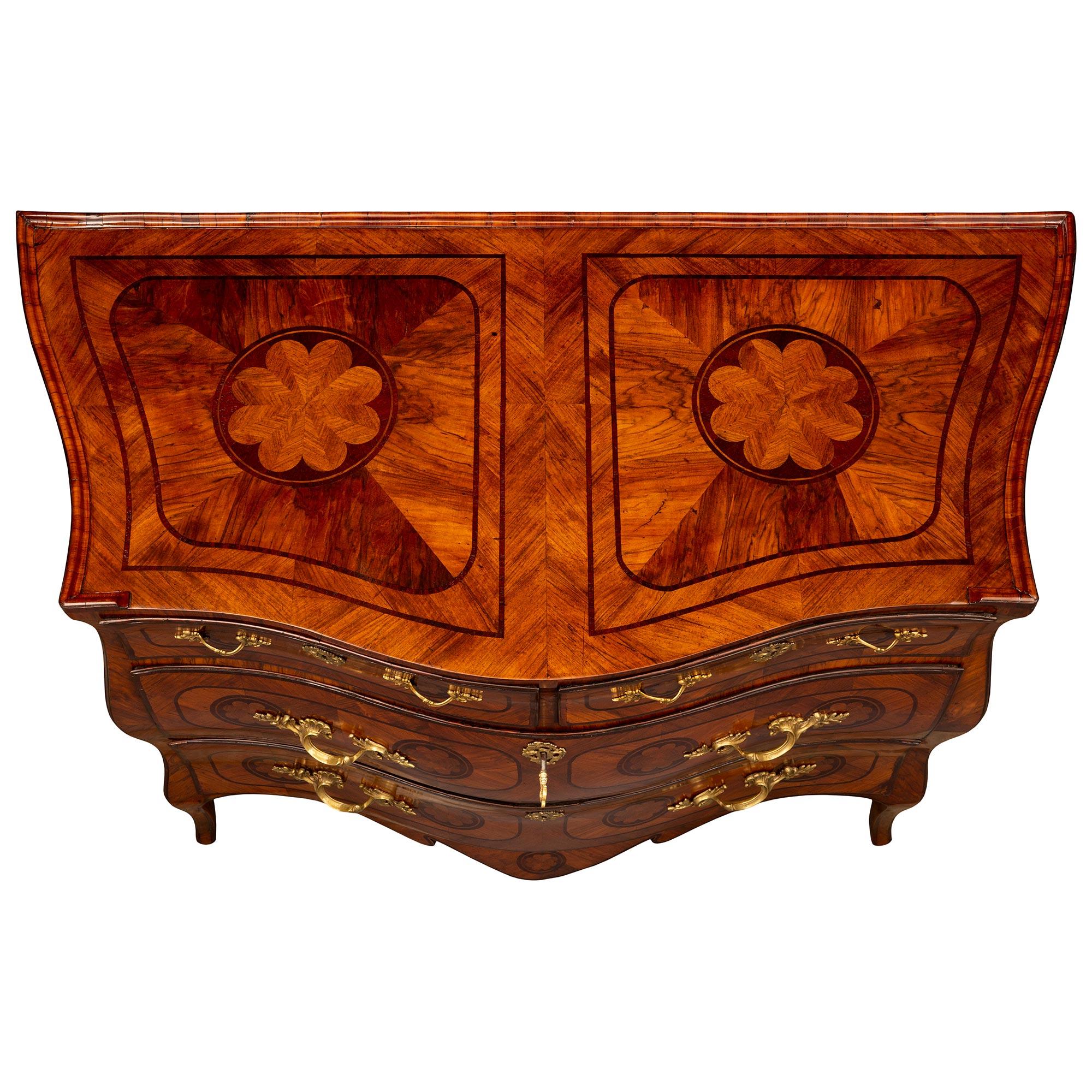A magnificent Italian 18th century Louis XV period Fruitwood, Kingwood, and ormolu commode from Naples, circa 1760. The four drawer chest is raised by elegant cabriole legs leading to a beautiful scalloped shaped apron. Each of the drawers is