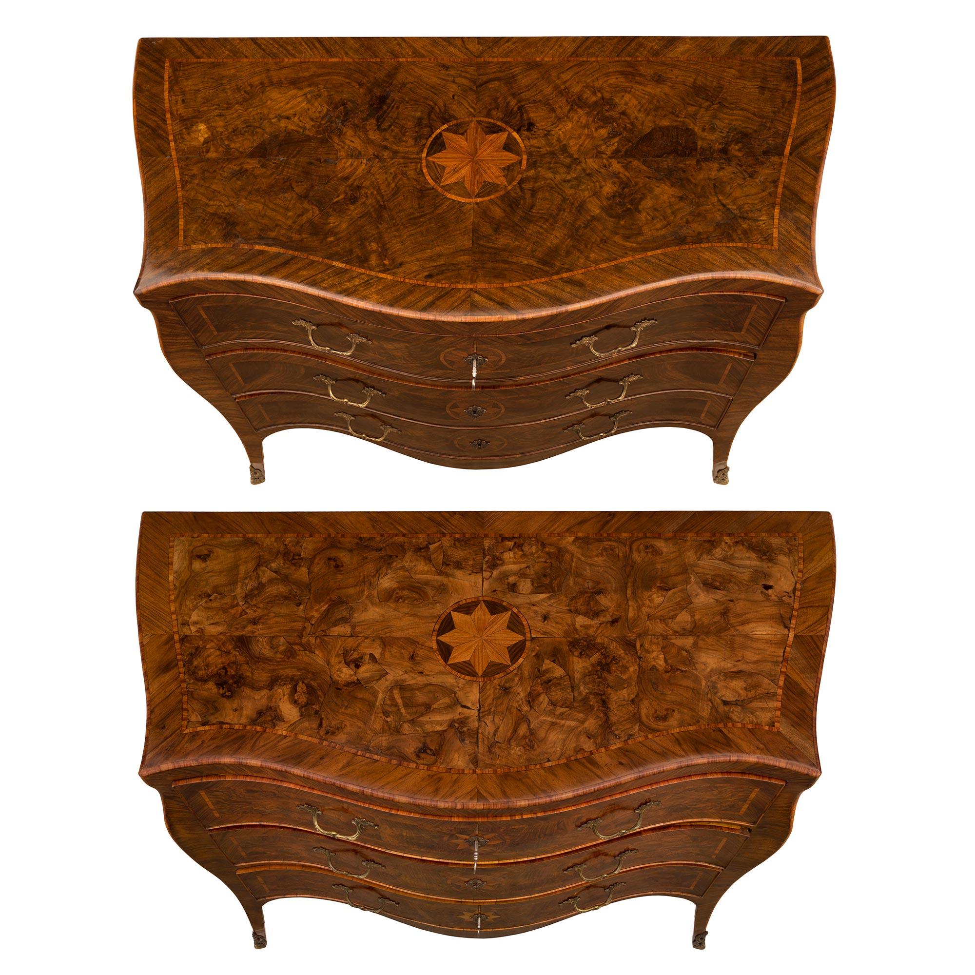 An exquisite his and hers pair of Italian 18th century Louis XV period Walnut and patinated bronze commodes. Each three drawer chest is raised by elegant lightly curved legs with fine pierced bronze foliate sabots below the most decorative arbalest