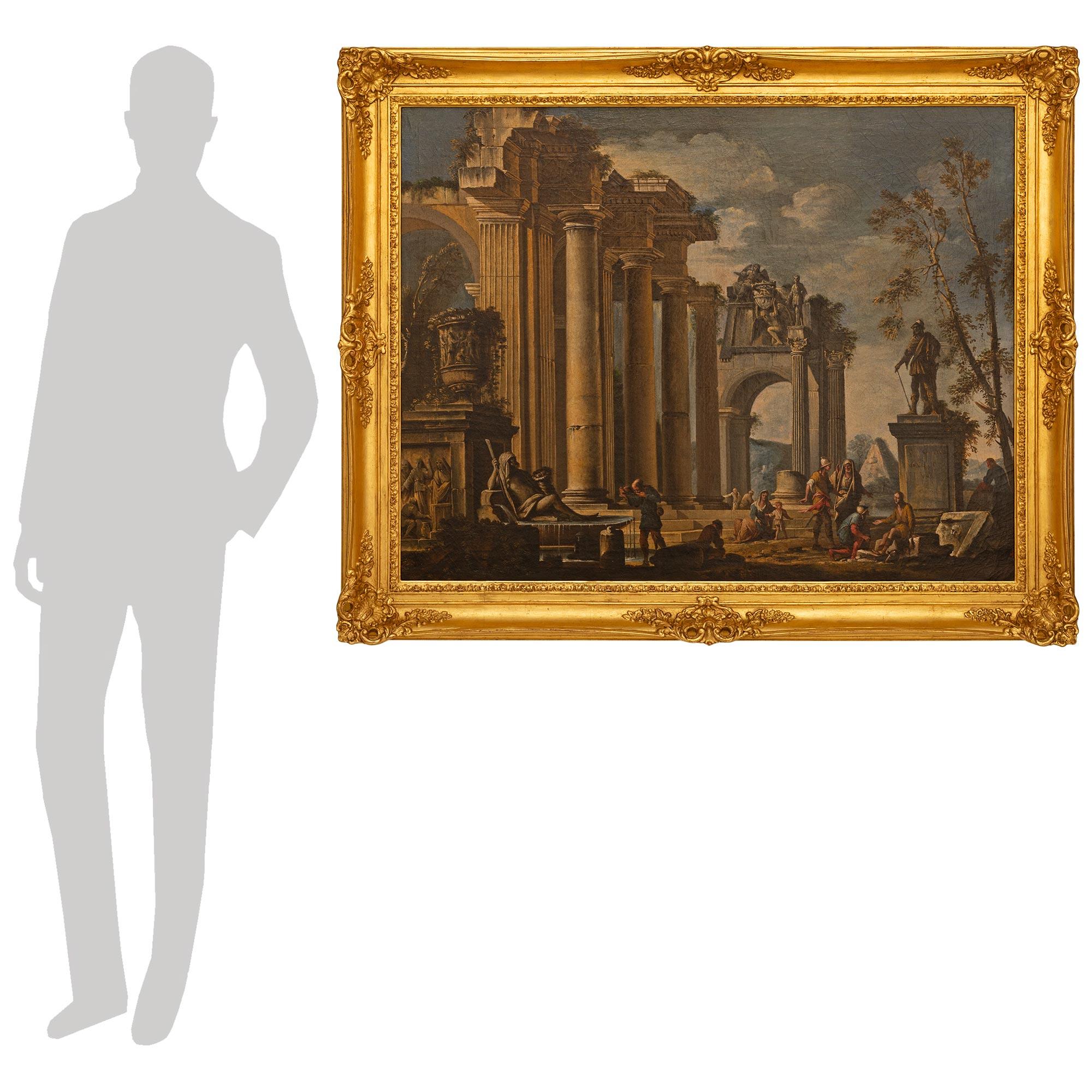 A decorative and statement making Italian 18th century Louis XV st. Oil on Canvas and Giltwood painting, in the manner of Giovanni Paolo Panini. This storytelling Capriccio style painting is wonderfully detailed with individuals conversing about a