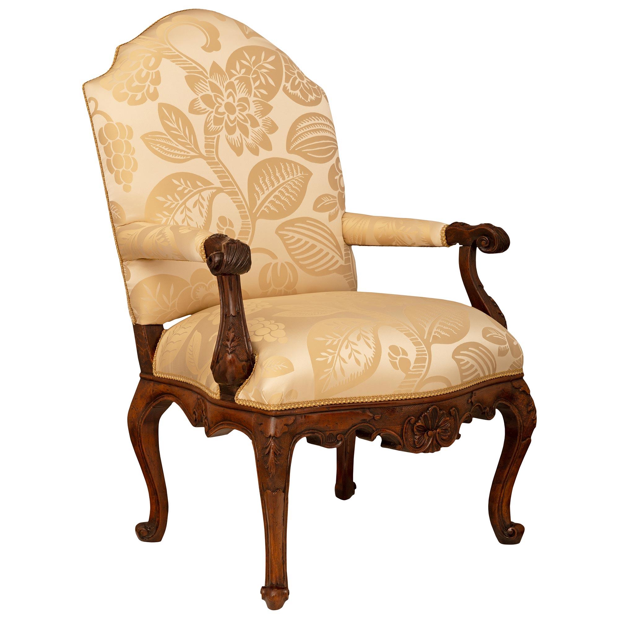 An impressive and finely detailed set of four Italian 18th century Louis XV st. Walnut armchairs. Each beautiful armchair is supported by four cabriole legs with scrolled feet and decorated with laurel vine carvings on each knee. The arbalest shaped