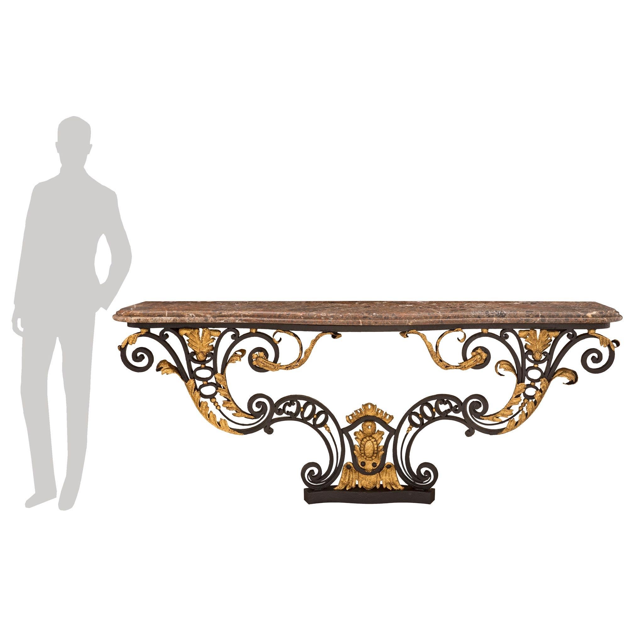 A stunning and extremely decorative Italian 18th century Louis XV st. wrought iron, gilt metal, and marble console. The wall mounted console is raised by a fine scalloped base from where the impressive pieced scrolled supports lead upwards. Each