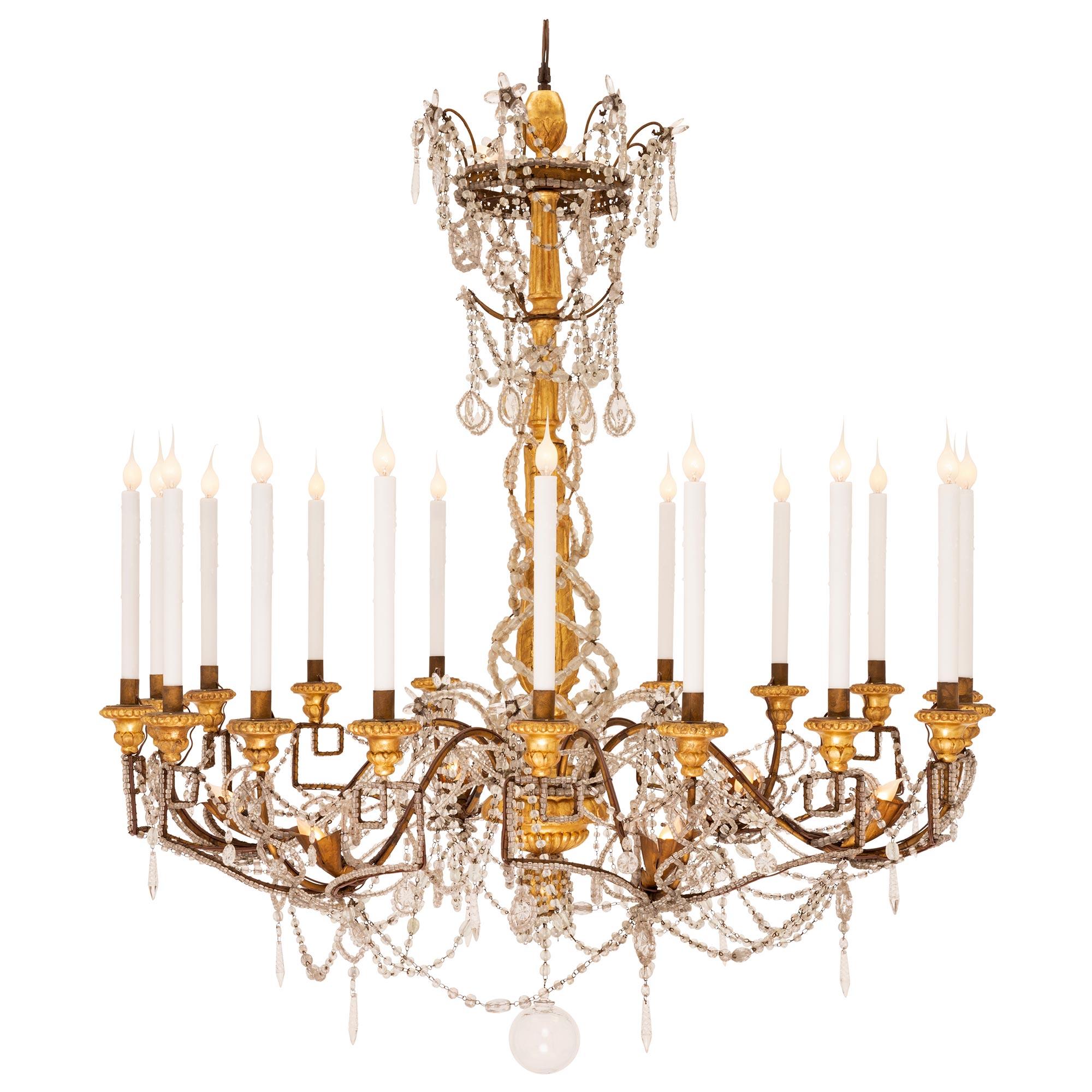 A stunning and extremely unique Italian 18th century Louis XVI period giltwood, gilt metal crystal, and cut glass chandelier, from Turin. The large scale eighteen arm and twenty eight light chandelier is centered by a lovely hand blown bottom glass