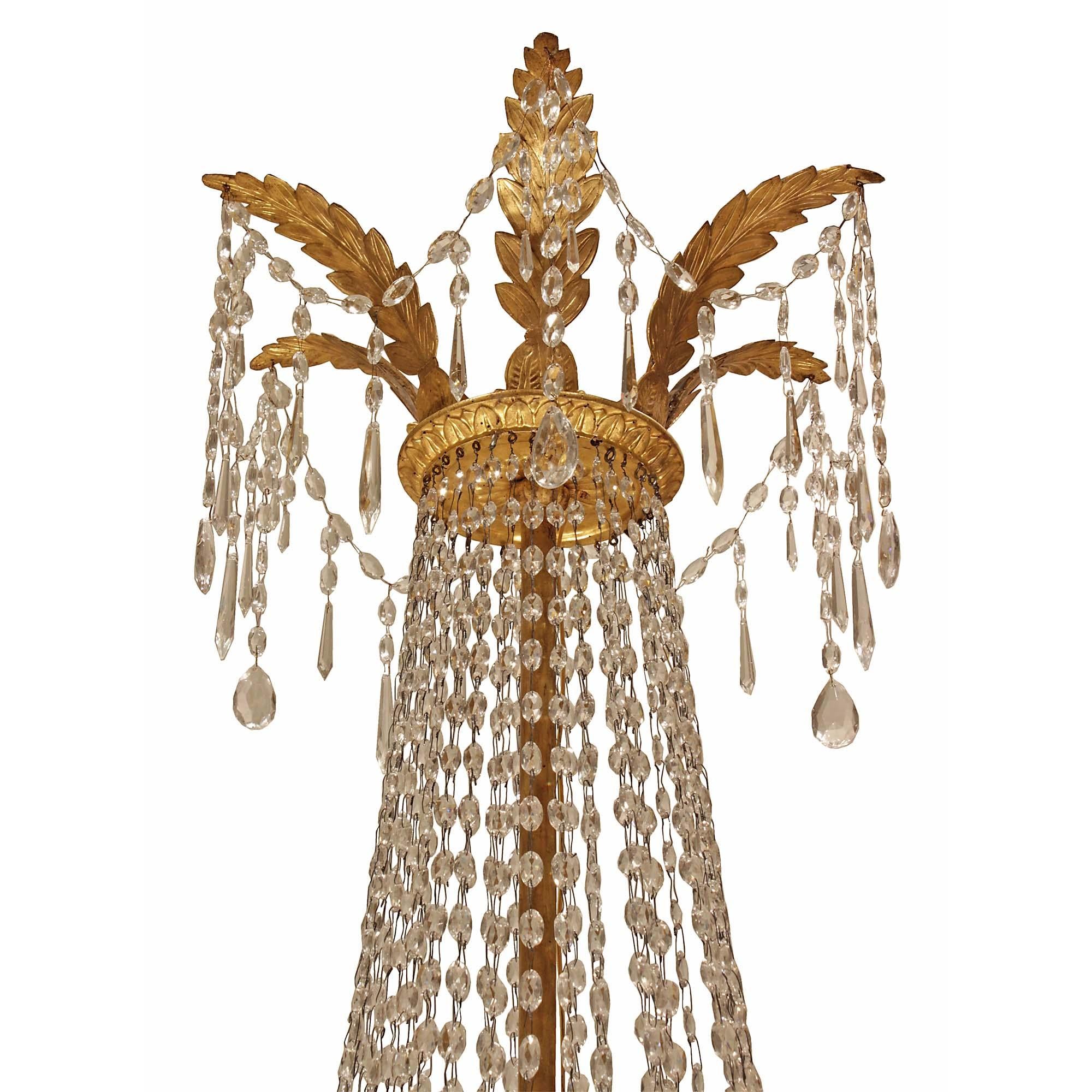 A unique and elegant Italian 18th century Louis XVI period gilt wood twelve light chandelier. This lovely air balloon shaped chandelier has a carved inverted bottom finial with garlands connecting to the central base. The circular base is decorated