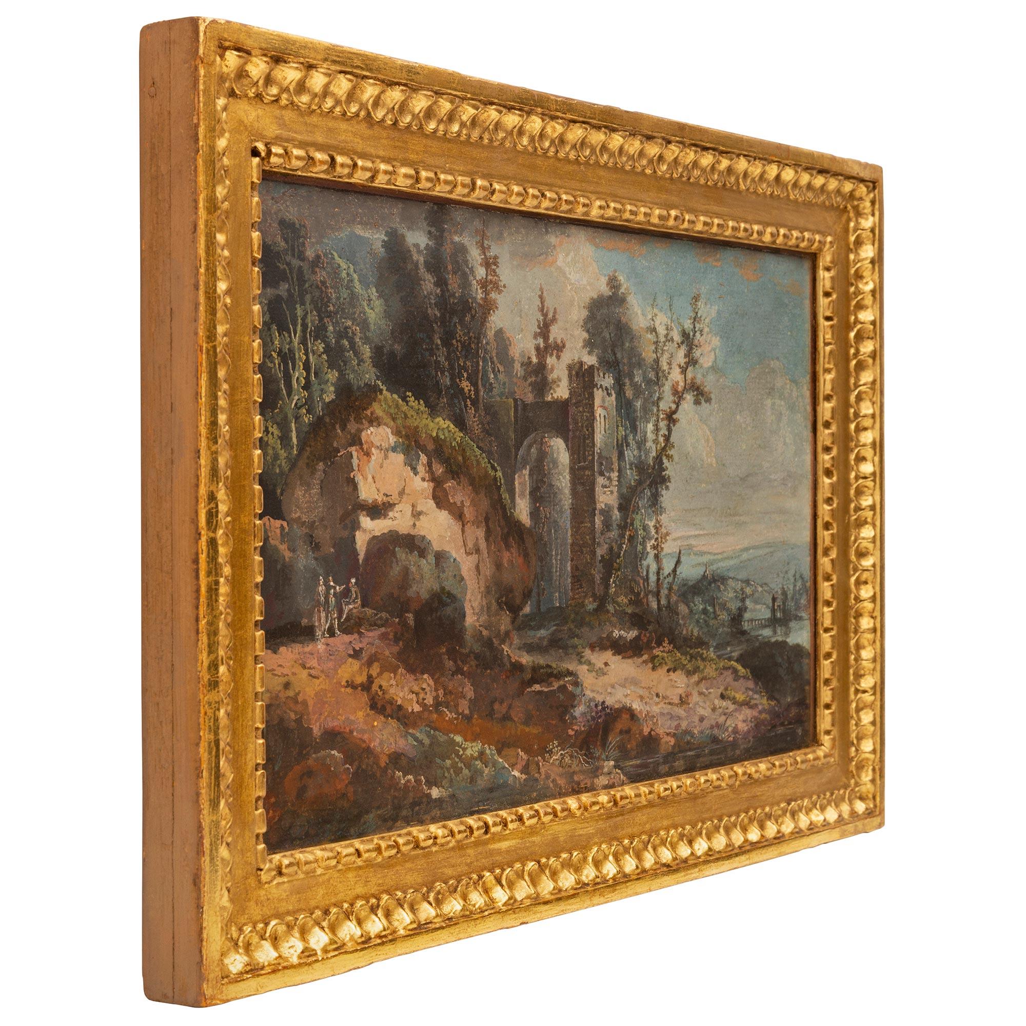 A charming Italian 18th century Louis XVI period gouache in its original giltwood frame. The wonderfully executed painting depicts a beautiful landscape of the Italian countryside with personages gathered next to a large boulder with a charming