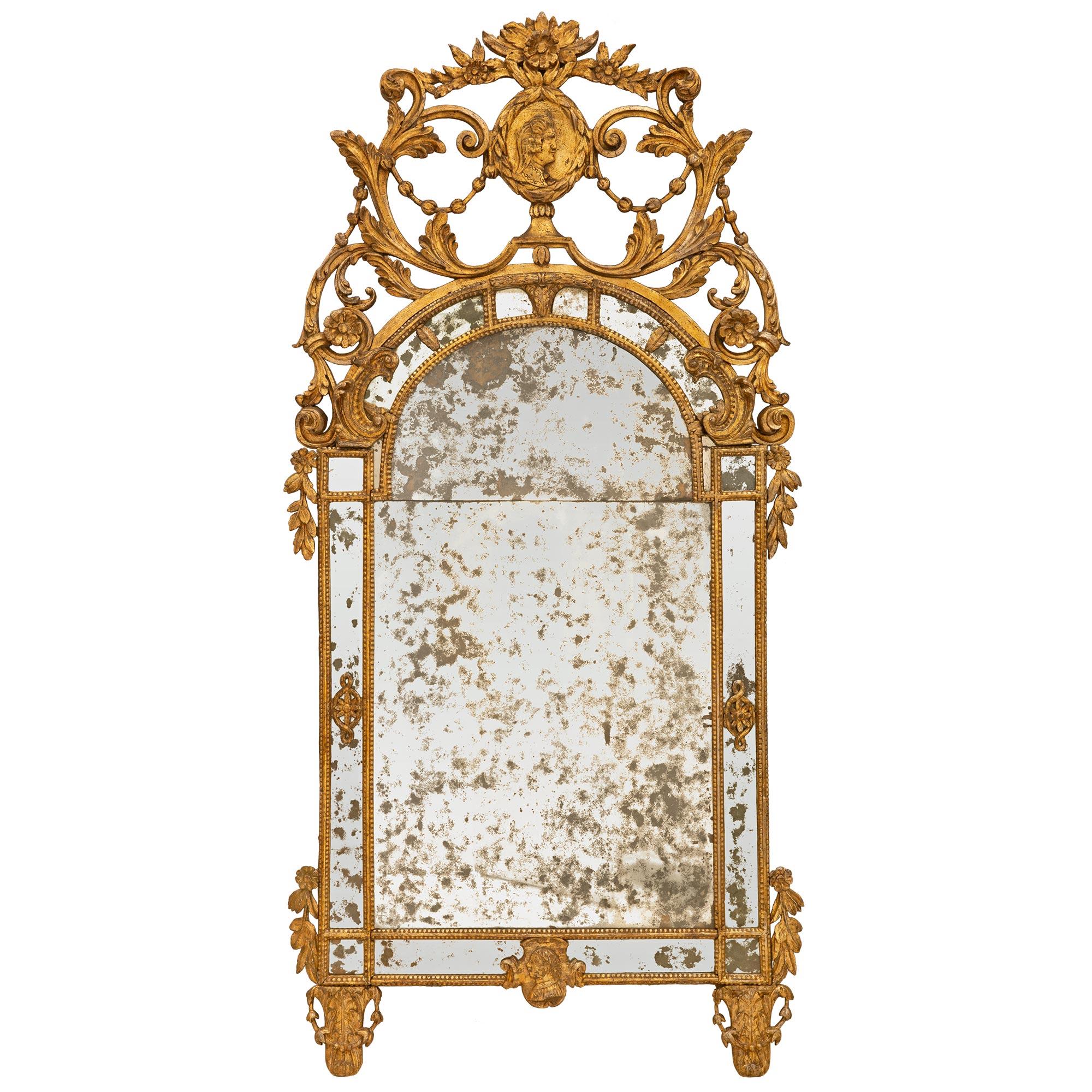 A magnificent Italian 18th century Louis XVI period Mecca mirror. The double frame mirror is raised on scrolled supports and foliate garlands at each corner, flanking a central male cameo, and design elements at each side. The rounded top is below