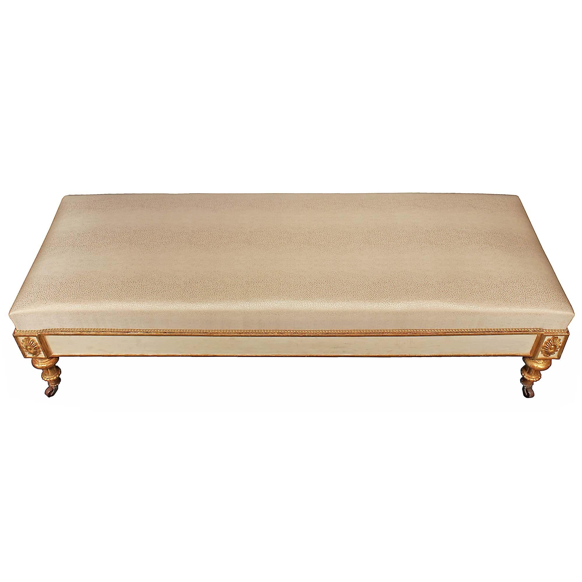 A stunning and unique Italian 18th century Louis XVI period patinated and giltwood bench. The bench is raised on square scrolled back supports and turned carved giltwood front supports with casters. The cream patinated frieze is decorated at the