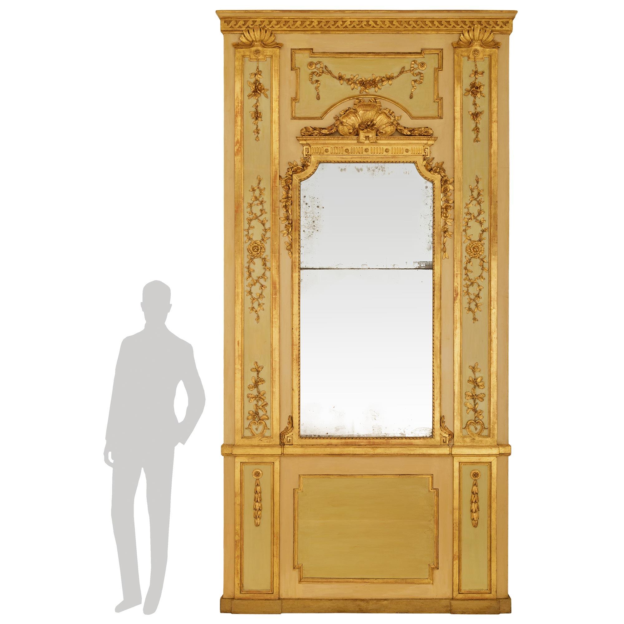 Miroir trumeau monumental et extrêmement décoratif en bois patiné et bois doré d'époque Louis XVI (Italie). Ce miroir palatial est surmonté d'un socle à patine olive foncée, au-dessous de trois panneaux en retrait encadrés de Sage contenant des